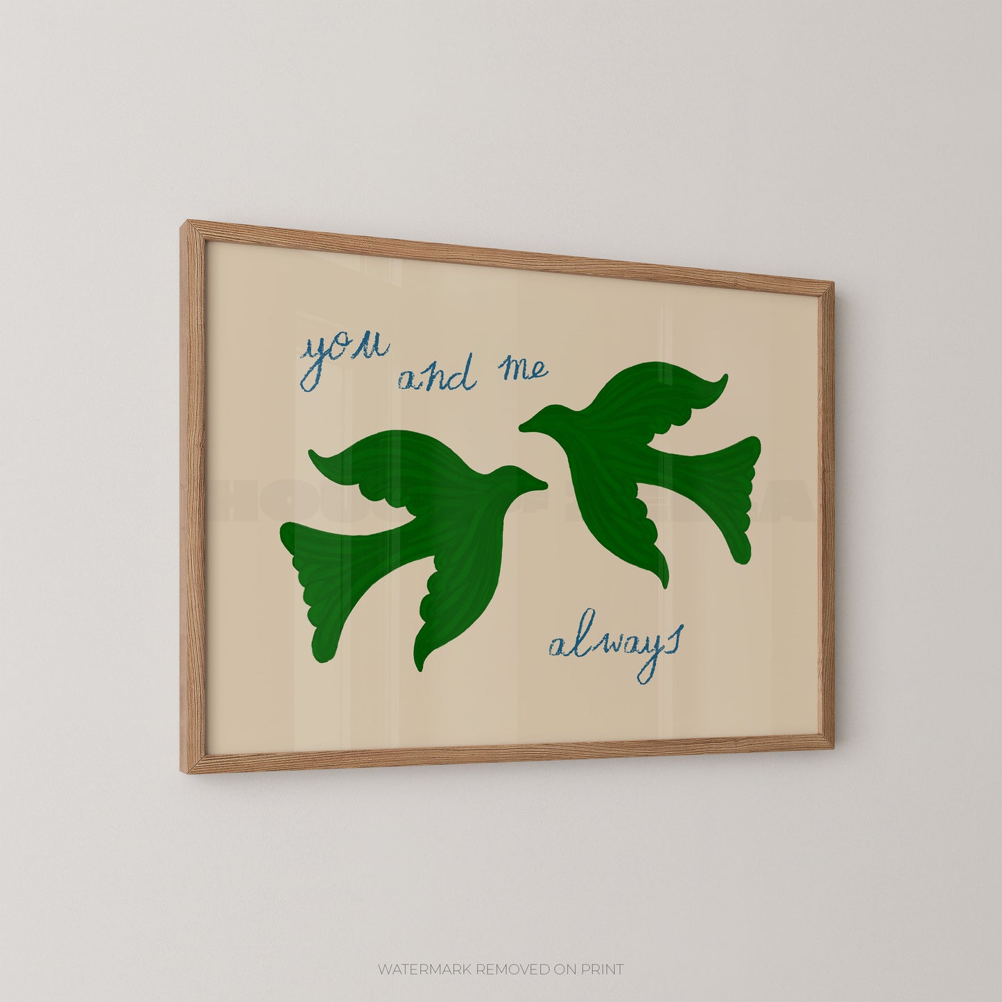 Framed wall art print with two green flying birds and the words 'you and me always' in blue script on a warm beige background, shown hanging on a light gray wall.