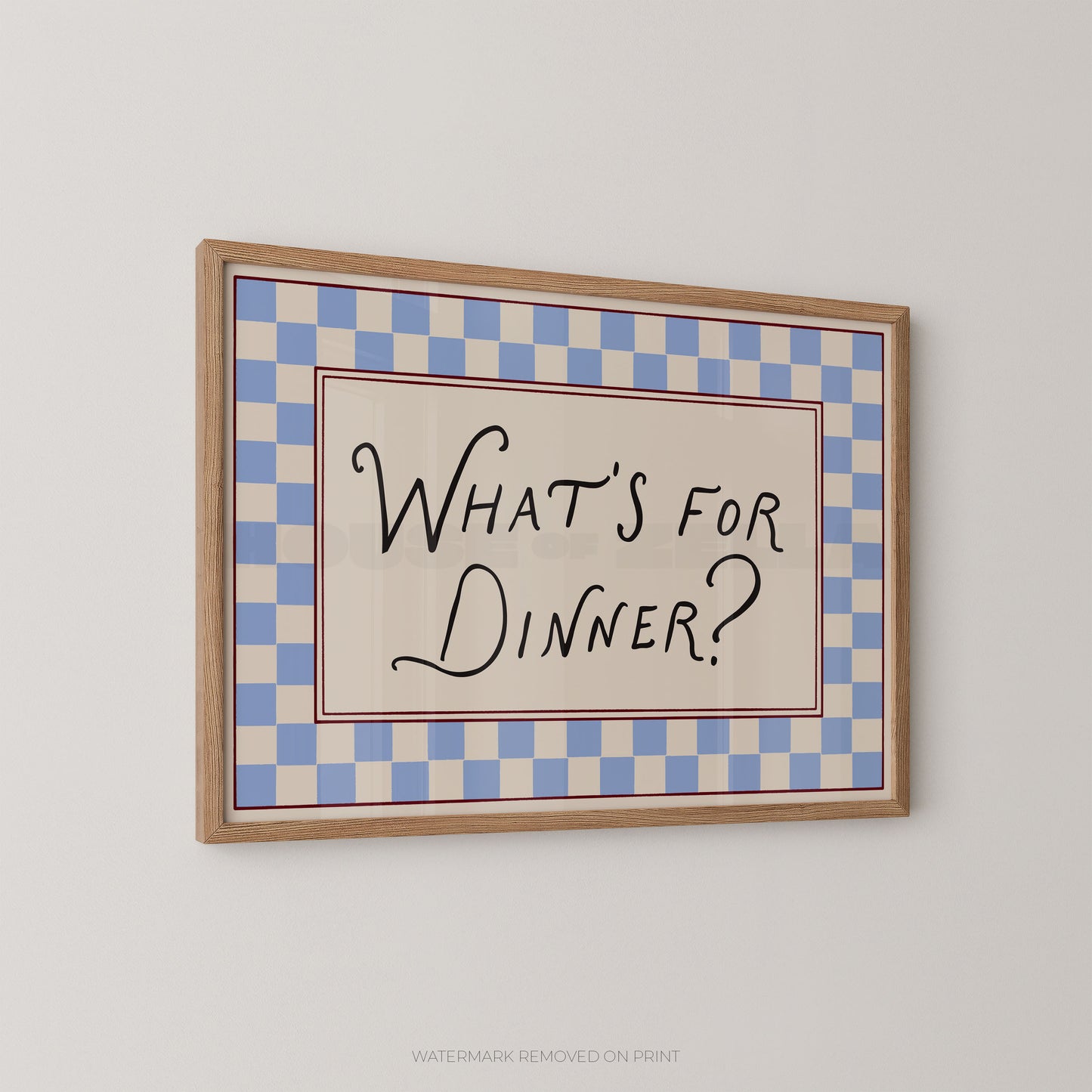 Framed checkered sign with 'What's for Dinner?' text on a plain wall.