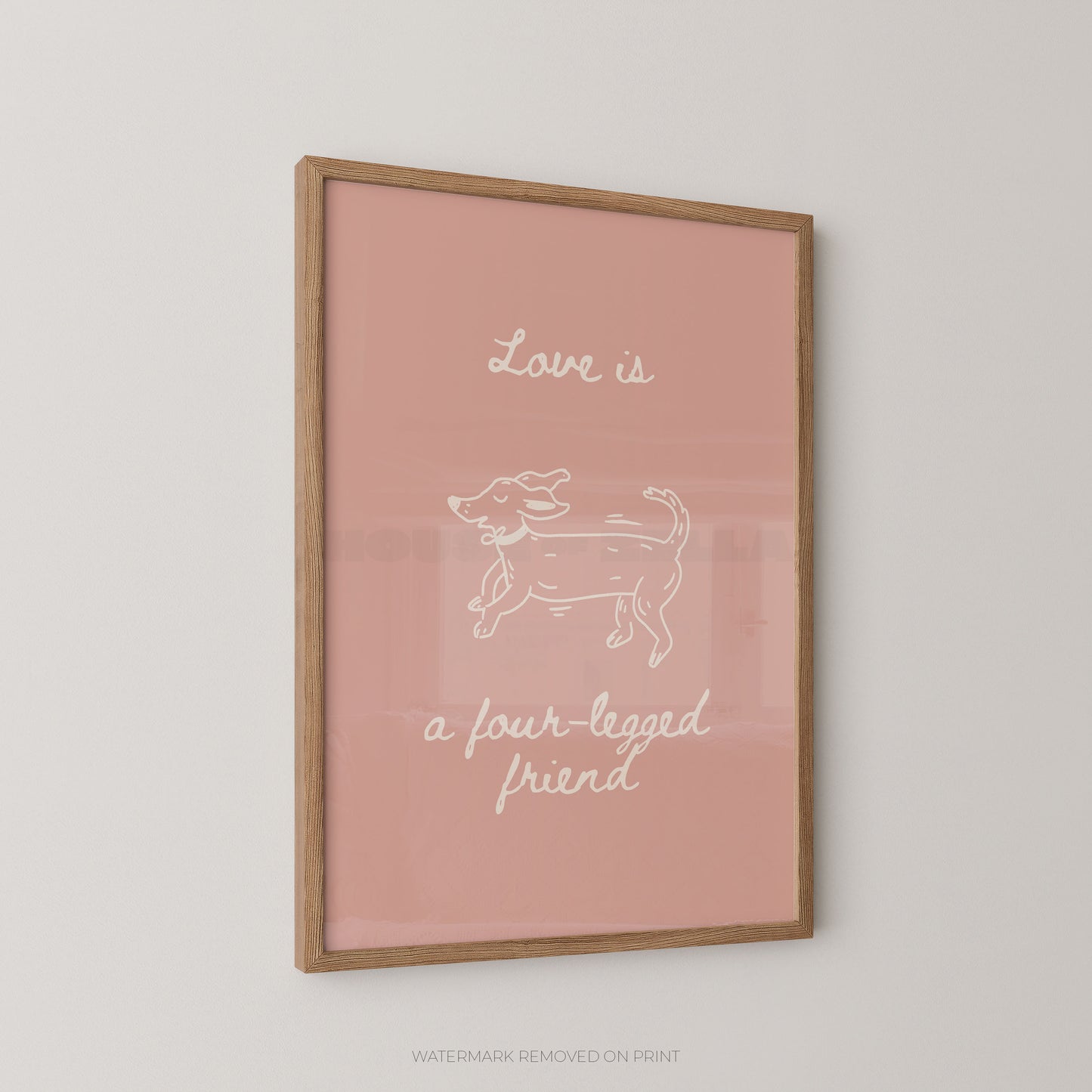 A framed art print with a dusty pink background, featuring a white line drawing of a dog and the text 'Love is a four-legged friend' in white script, enclosed in a light wood frame.