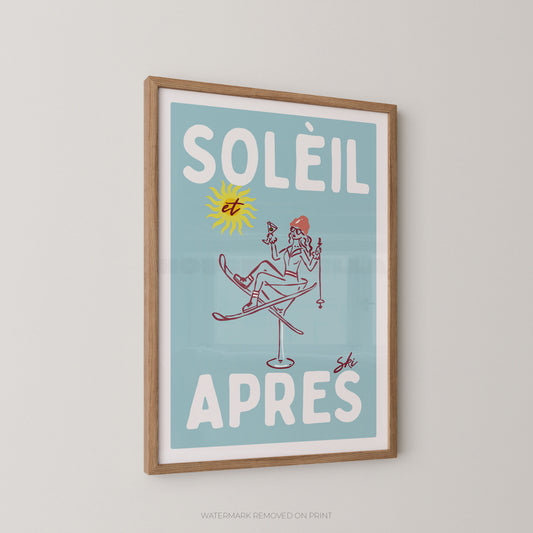 A framed art print featuring a retro winter illustration with the French text 'SOLÉIL et APRES'. The print has a light blue background, white lettering, a yellow sun, and a red-haired skier, enclosed in a light wood frame and hanging on a neutral wall.