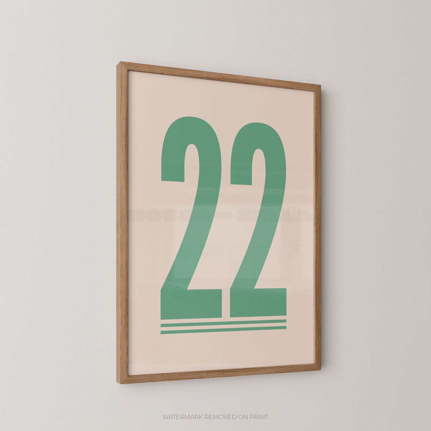 Framed wall art print with the number 22 in green on a light beige background, shown hanging on a light gray wall.