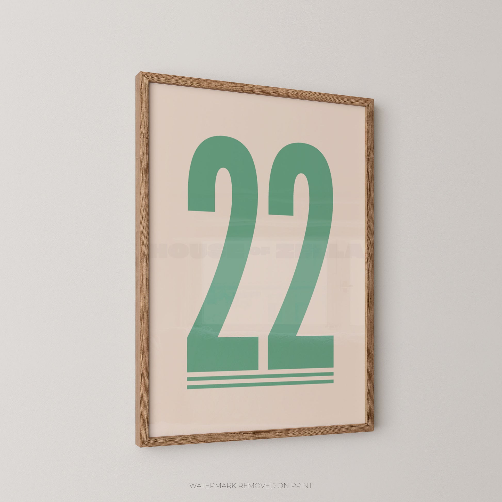 Framed wall art print with the number 22 in green on a light beige background, shown hanging on a light gray wall.