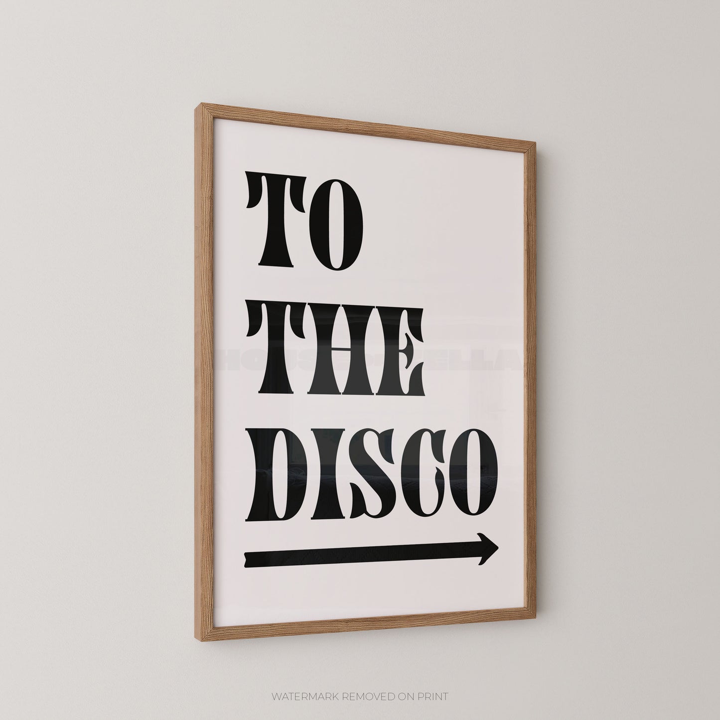 Framed wall art print with the words “TO THE DISCO” in large black letters and a black arrow below, shown hanging on a light gray wall.