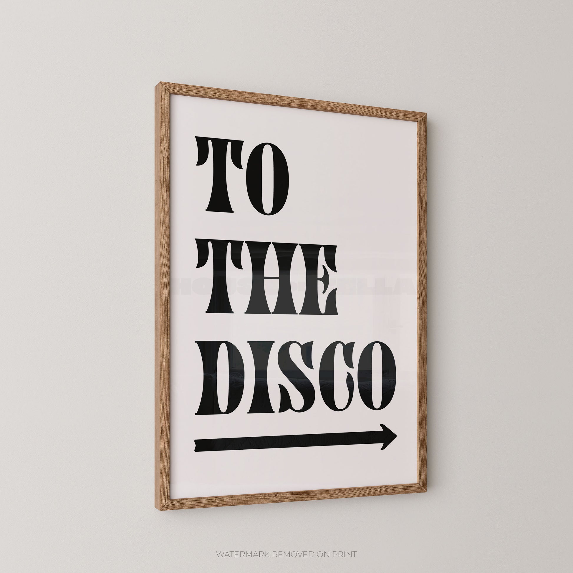 Framed wall art print with the words “TO THE DISCO” in large black letters and a black arrow below, shown hanging on a light gray wall.