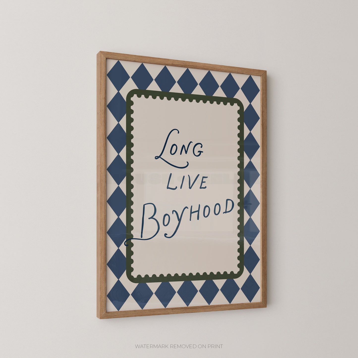 Framed wall art print with the phrase 'Long Live Boyhood' in blue script, surrounded by a navy and white diamond pattern and a green inner border, shown in a light wood frame against a light gray wall.