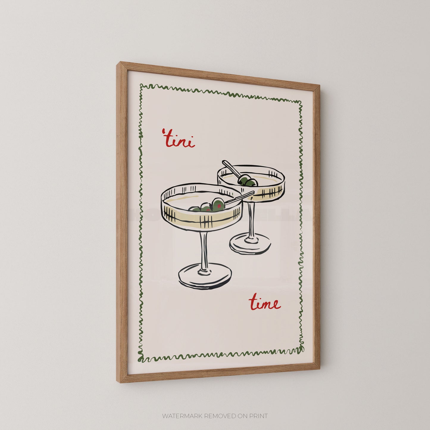 Framed wall art print featuring a hand-drawn illustration of two margarita glasses with olives, bordered by a green zigzag line, with the words "tini time" in red script on a cream background, shown in a light wood frame against a light gray wall.