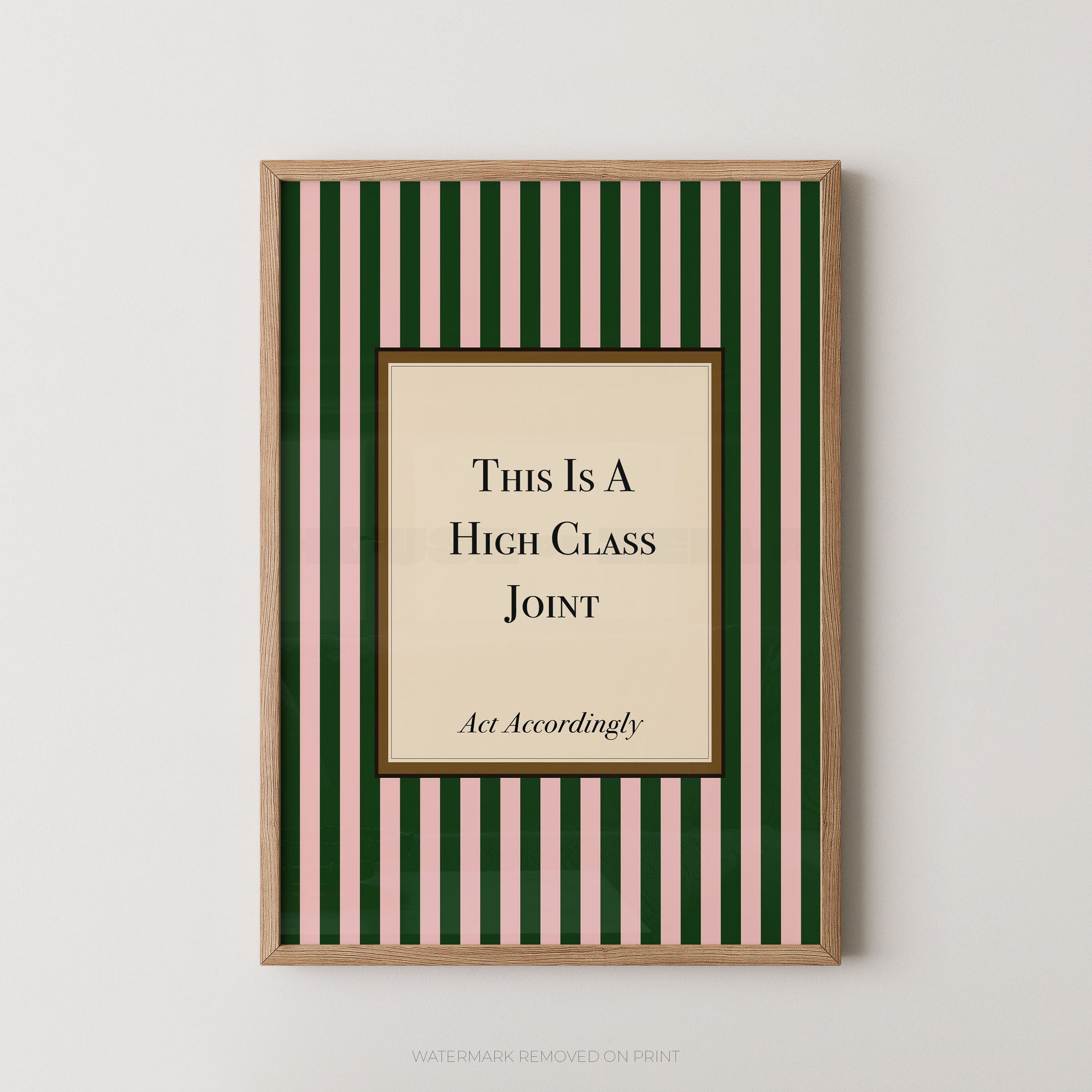 A framed humorous wall art print featuring a beige central panel with the text 'This Is A High Class Joint' and 'Act Accordingly' on a background of dark green and light pink vertical stripes, enclosed in a light wood frame.