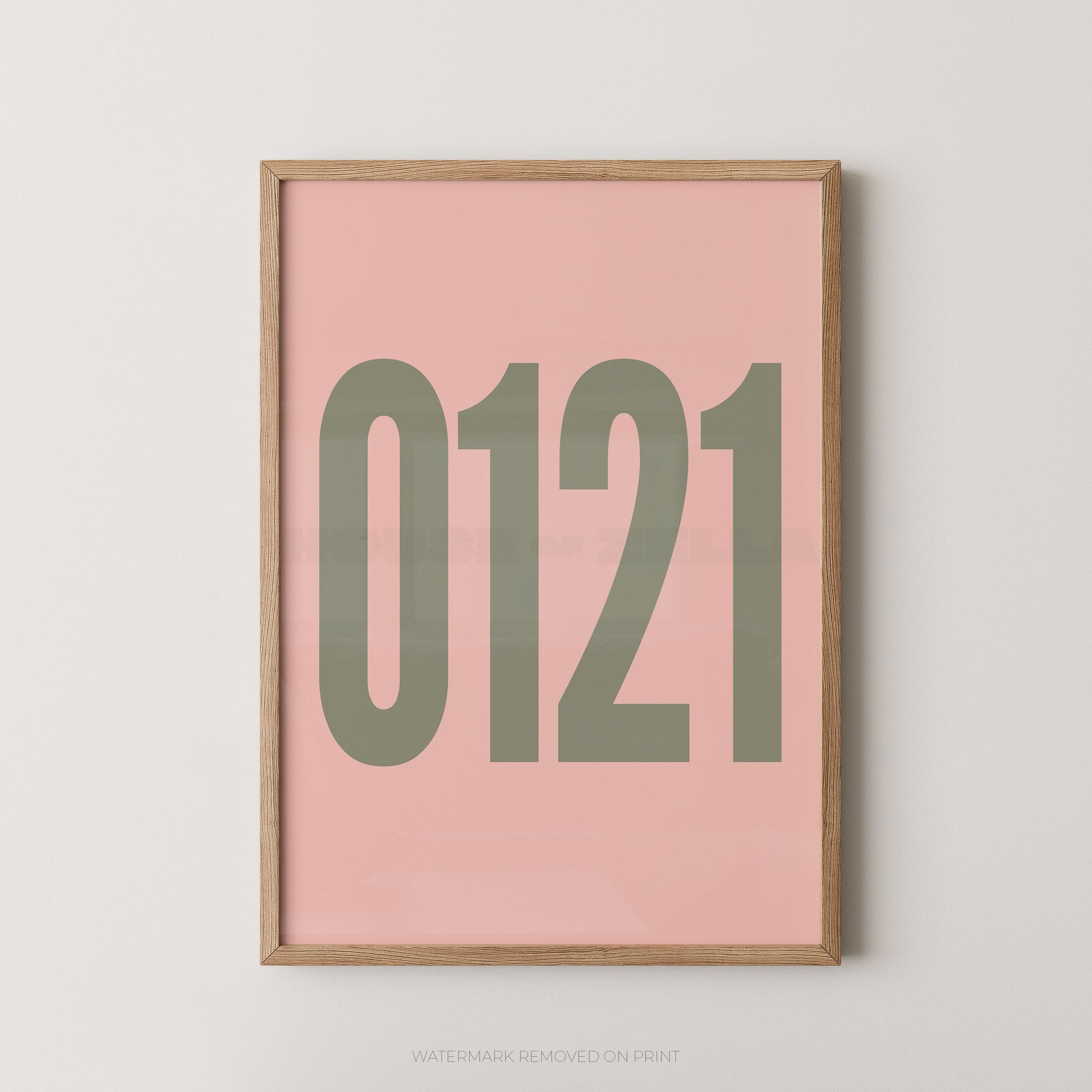 A framed minimalist art print featuring '0121' in gold on a light pink background, enclosed in a natural wood frame.