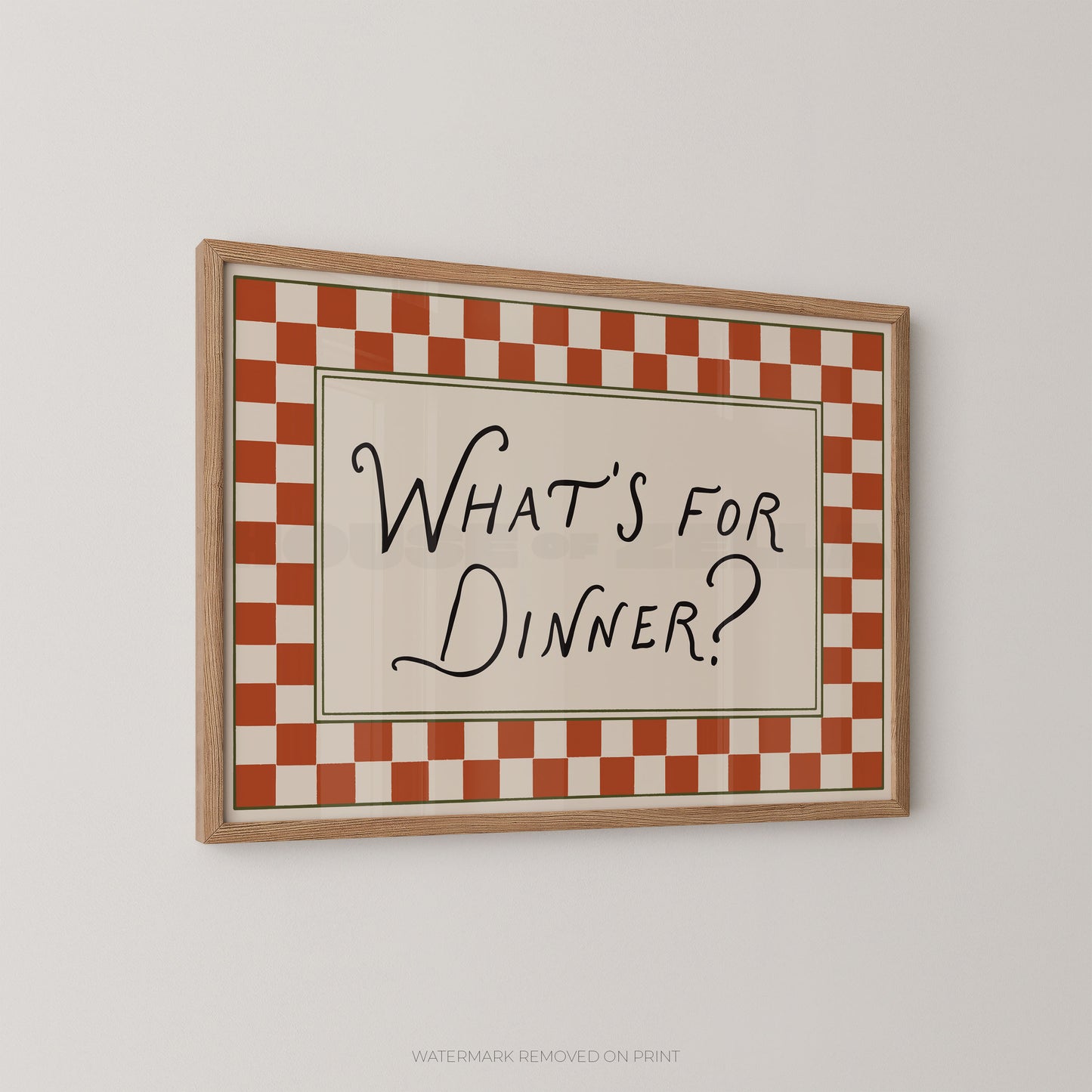 Framed checkered sign with 'What's for Dinner?' text on a plain wall.