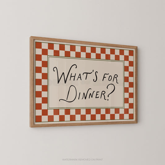 Framed checkered sign with 'What's for Dinner?' text on a plain wall.