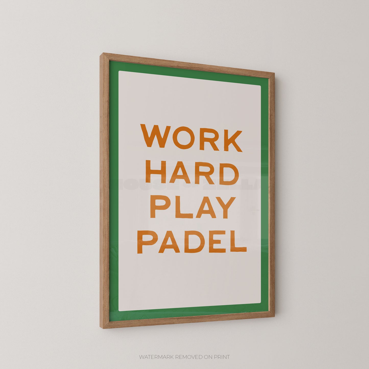 "Work Hard Play Padel bold typography sports wall art print with orange lettering on a cream background with a green border, displayed at an angle in an oak frame"

