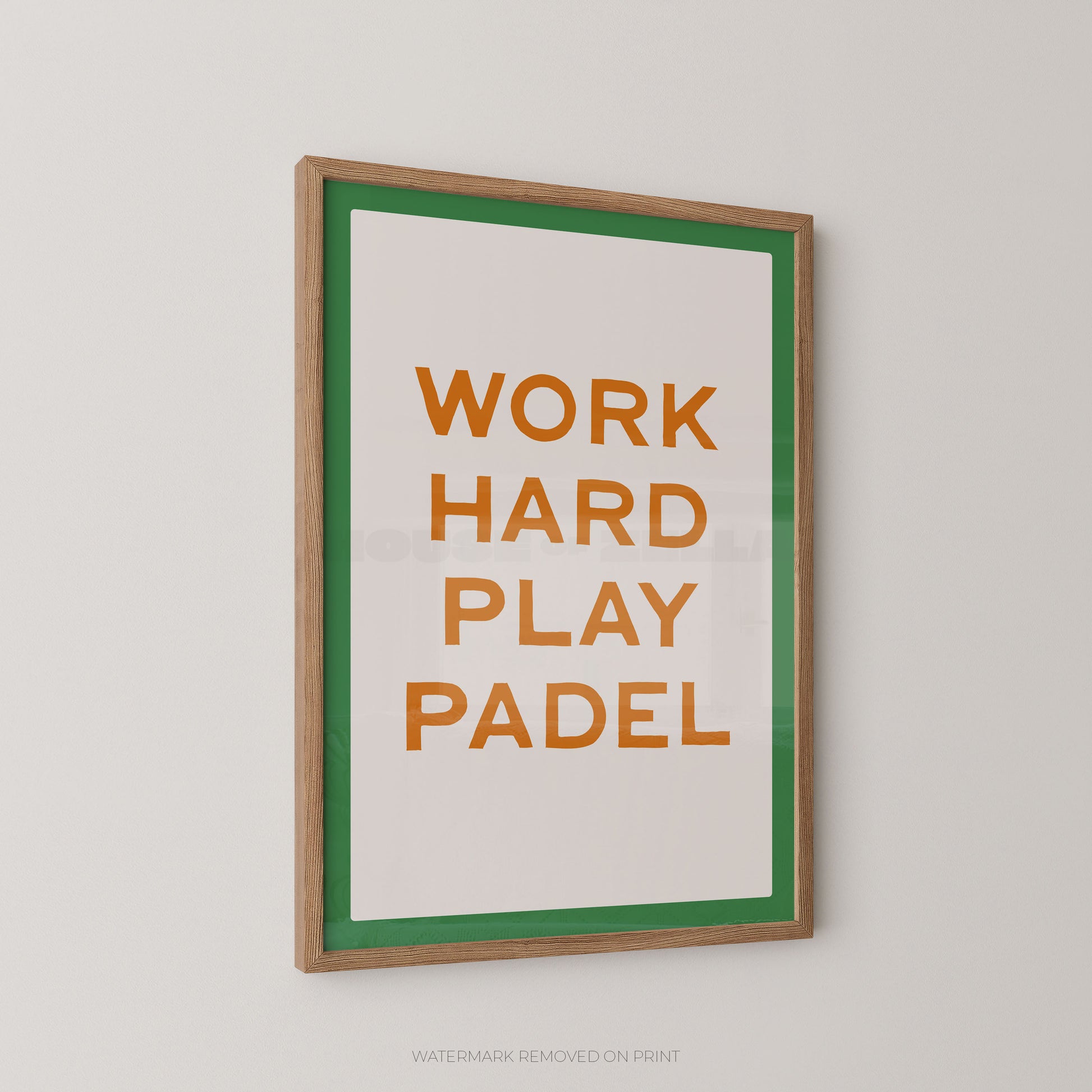 "Work Hard Play Padel bold typography sports wall art print with orange lettering on a cream background with a green border, displayed at an angle in an oak frame"

