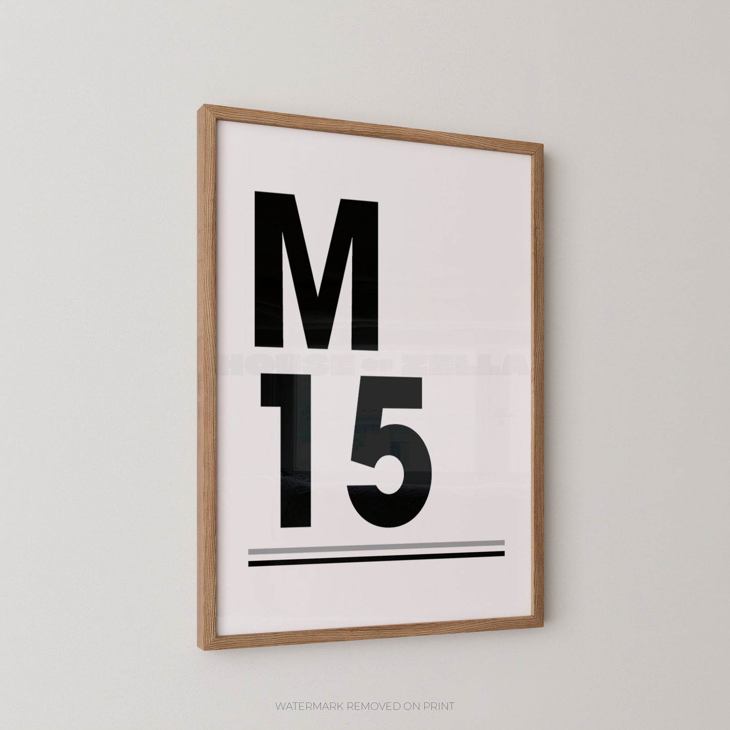Framed minimalist wall art print with the letter M and number 15 in bold black on a white background, shown hanging on a light gray wall.