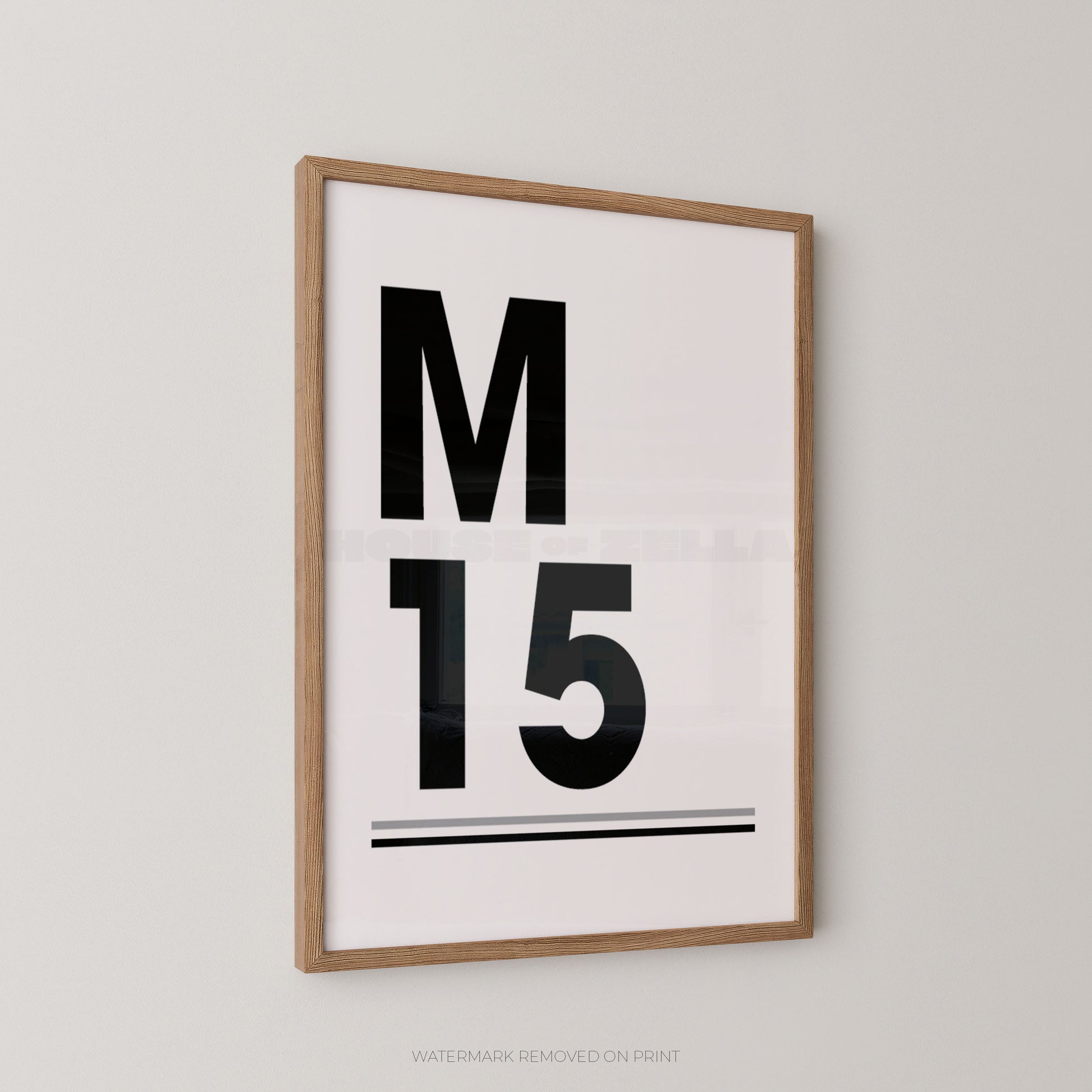 Framed minimalist wall art print with the letter M and number 15 in bold black on a white background, shown hanging on a light gray wall.