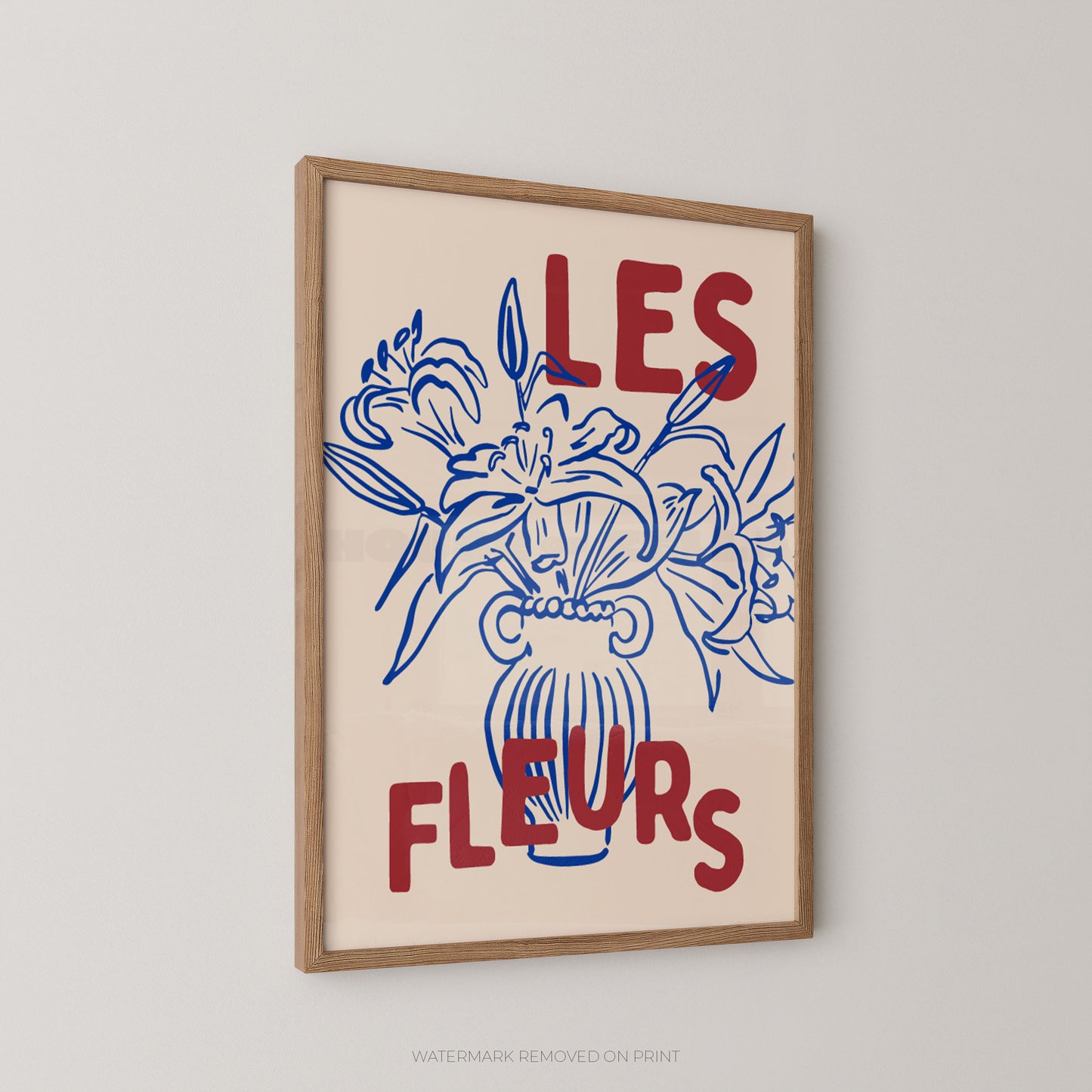 A framed art print featuring a blue line drawing of lilies in a vase with the red text 'LES FLEURS' on a cream background, hung on a light gray wall.
