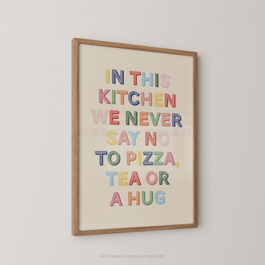 Framed wall art print with the phrase “IN THIS KITCHEN WE NEVER SAY NO TO PIZZA, TEA OR A HUG” in colorful raised letters on a cream background, shown hanging on a light gray wall.