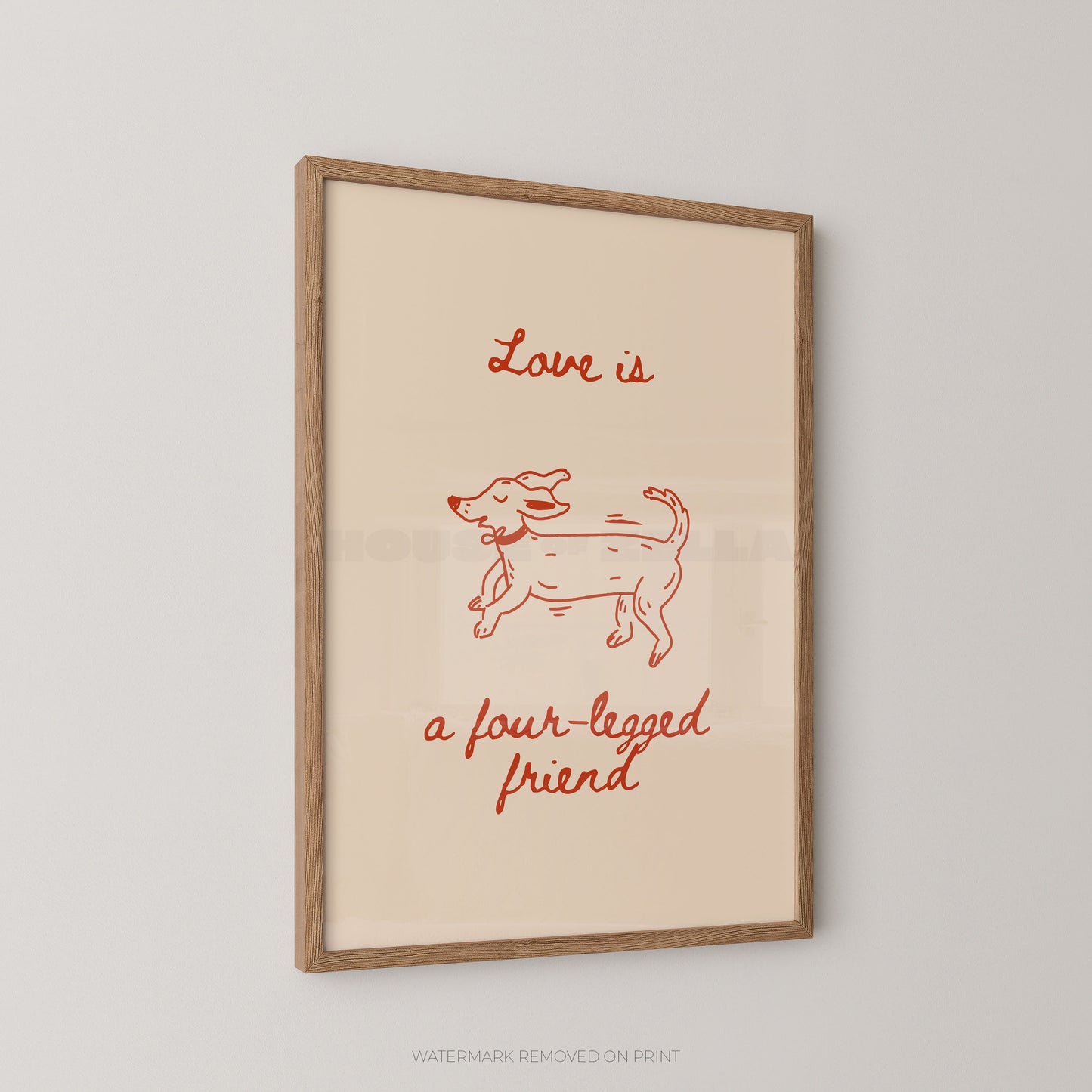 A framed art print featuring a minimalist red line drawing of a dog and the text 'Love is a four-legged friend' on a warm cream background, enclosed in a light natural wood frame and shown hanging on a light gray wall.