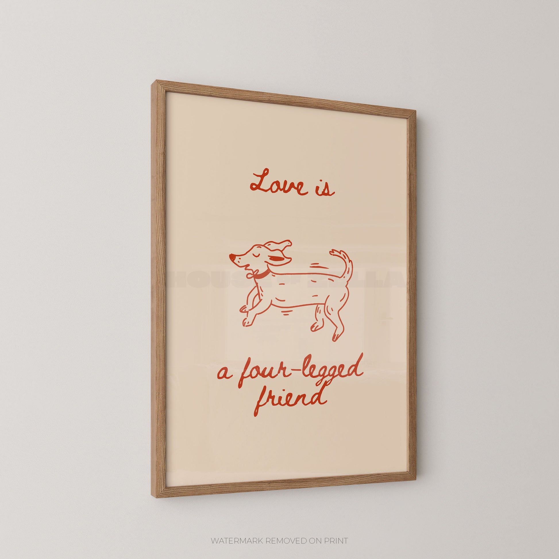 A framed art print featuring a minimalist red line drawing of a dog and the text 'Love is a four-legged friend' on a warm cream background, enclosed in a light natural wood frame and shown hanging on a light gray wall.