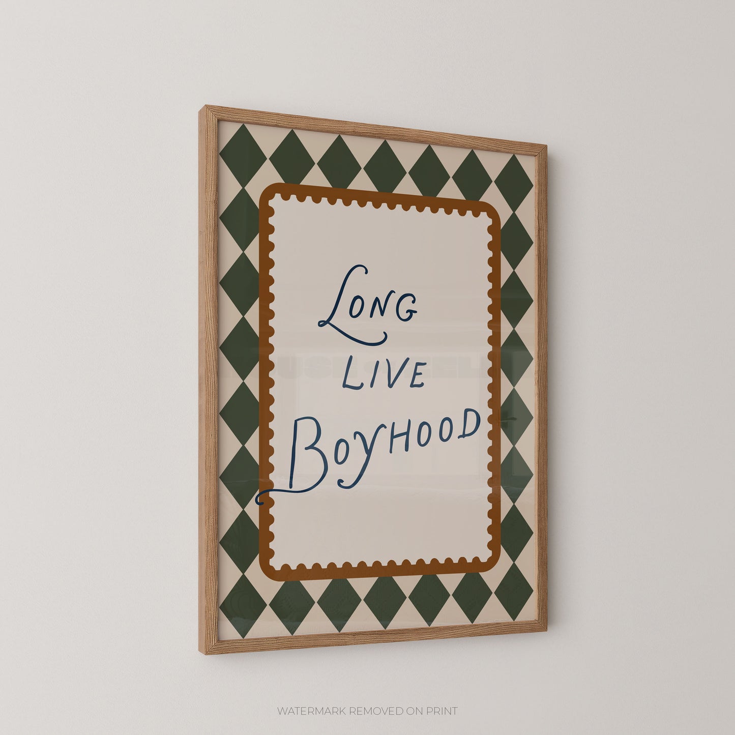 Framed wall art print with the phrase 'Long Live Boyhood' in blue script, surrounded by a brown scalloped inner border and a green-and-cream diamond pattern, shown hanging on a light gray wall.