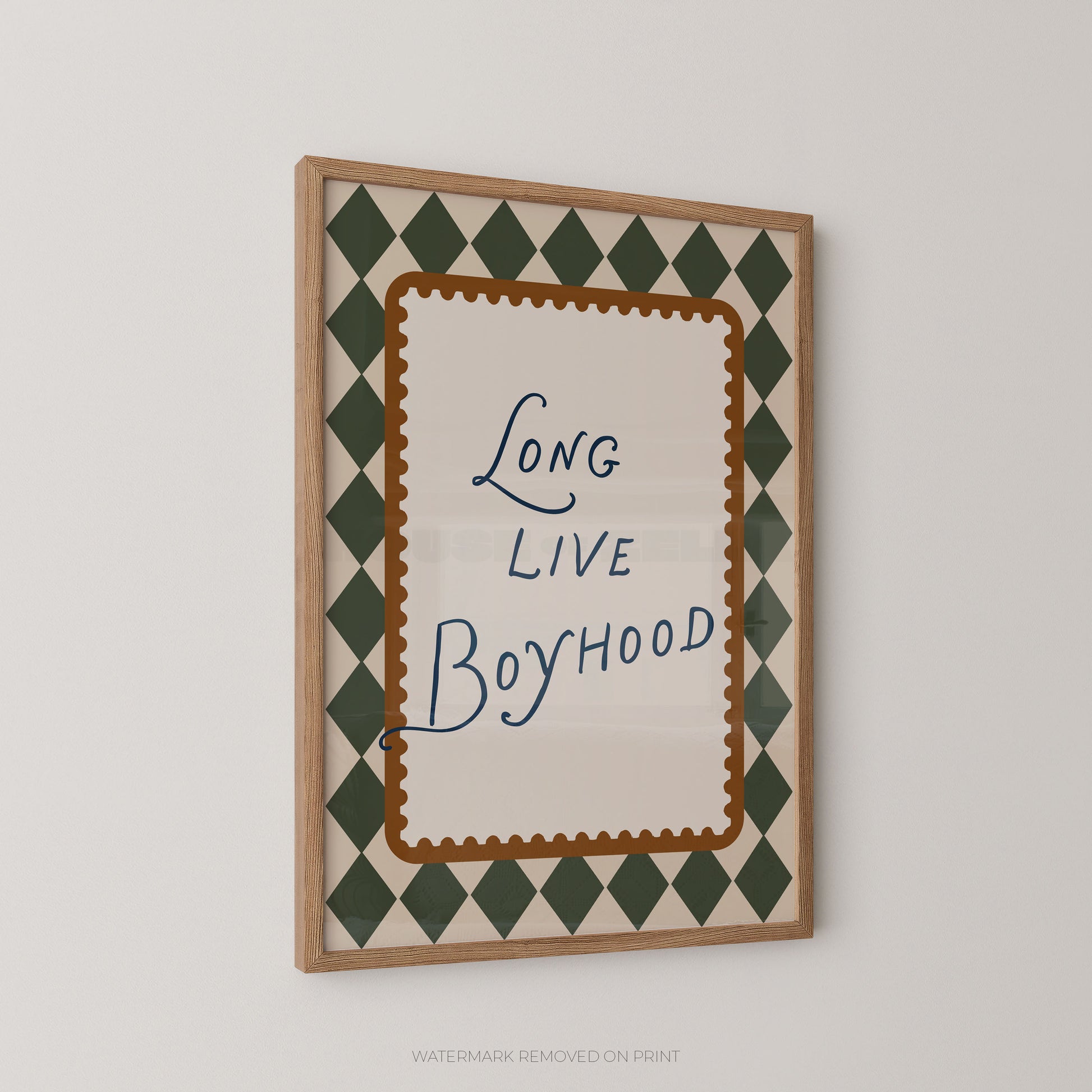 Framed wall art print with the phrase 'Long Live Boyhood' in blue script, surrounded by a brown scalloped inner border and a green-and-cream diamond pattern, shown hanging on a light gray wall.