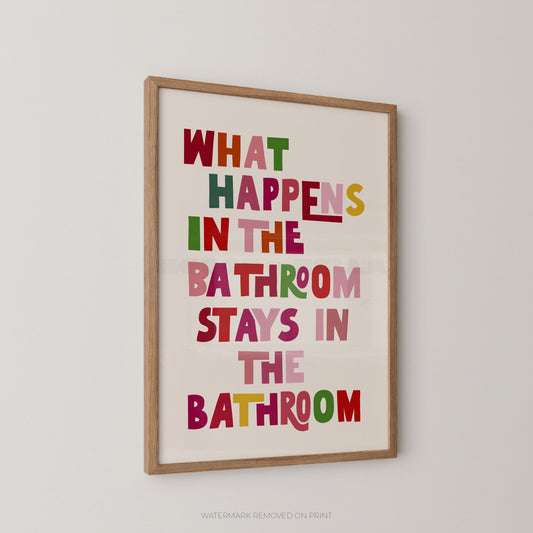 Funny bathroom wall art print in a wood frame – playful multicoloured chunky typography on a cream background reading "What Happens In The Bathroom Stays In The Bathroom"