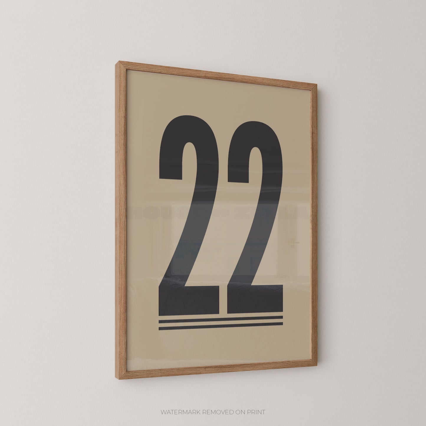 Framed minimalist wall art featuring the number 22 in bold black typography on a warm beige background, enclosed in a light natural wood frame and shown hanging on a plain light wall.