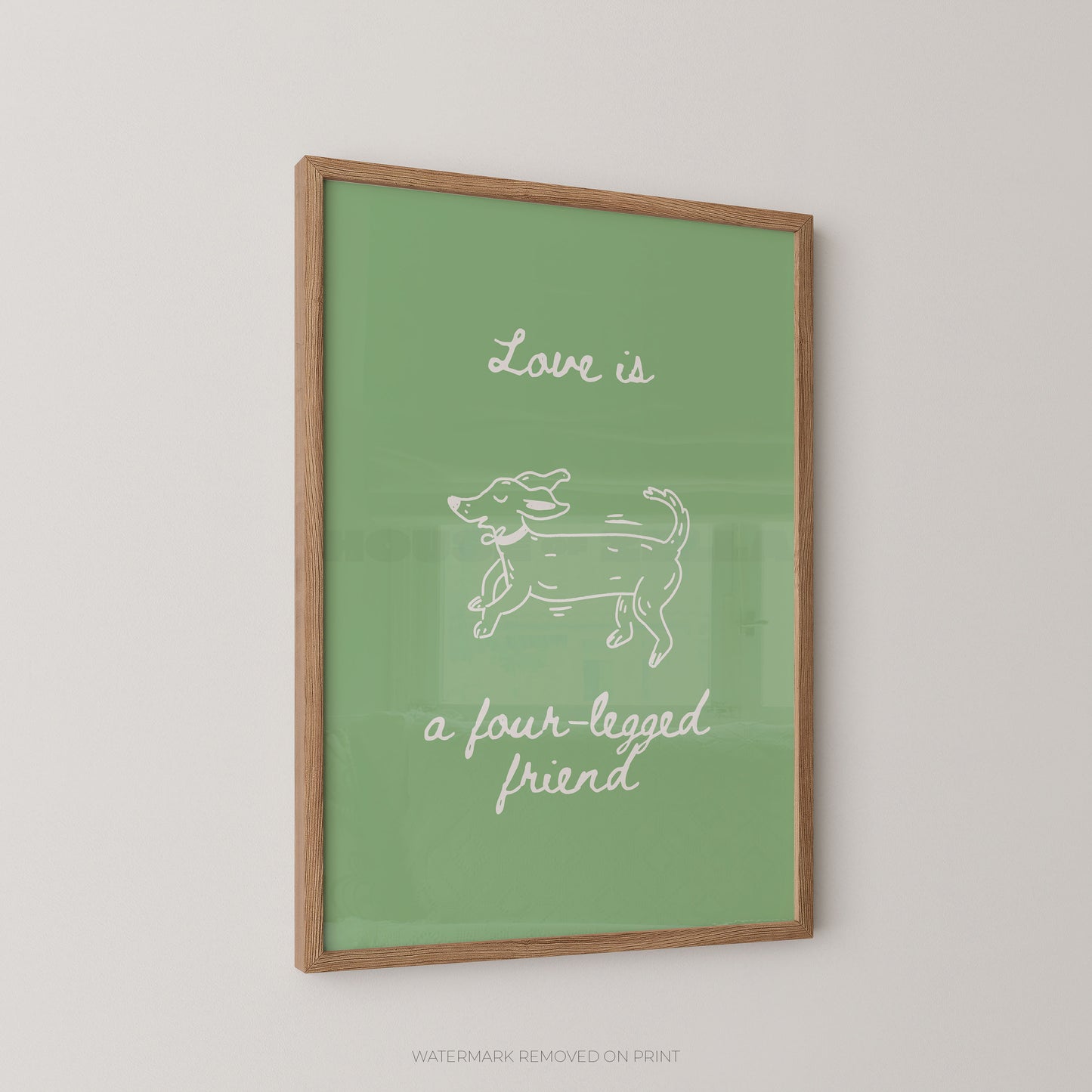 A framed art print featuring a green background with a white line drawing of a dog and the text 'Love is a four-legged friend' in white script, displayed on a light gray wall.