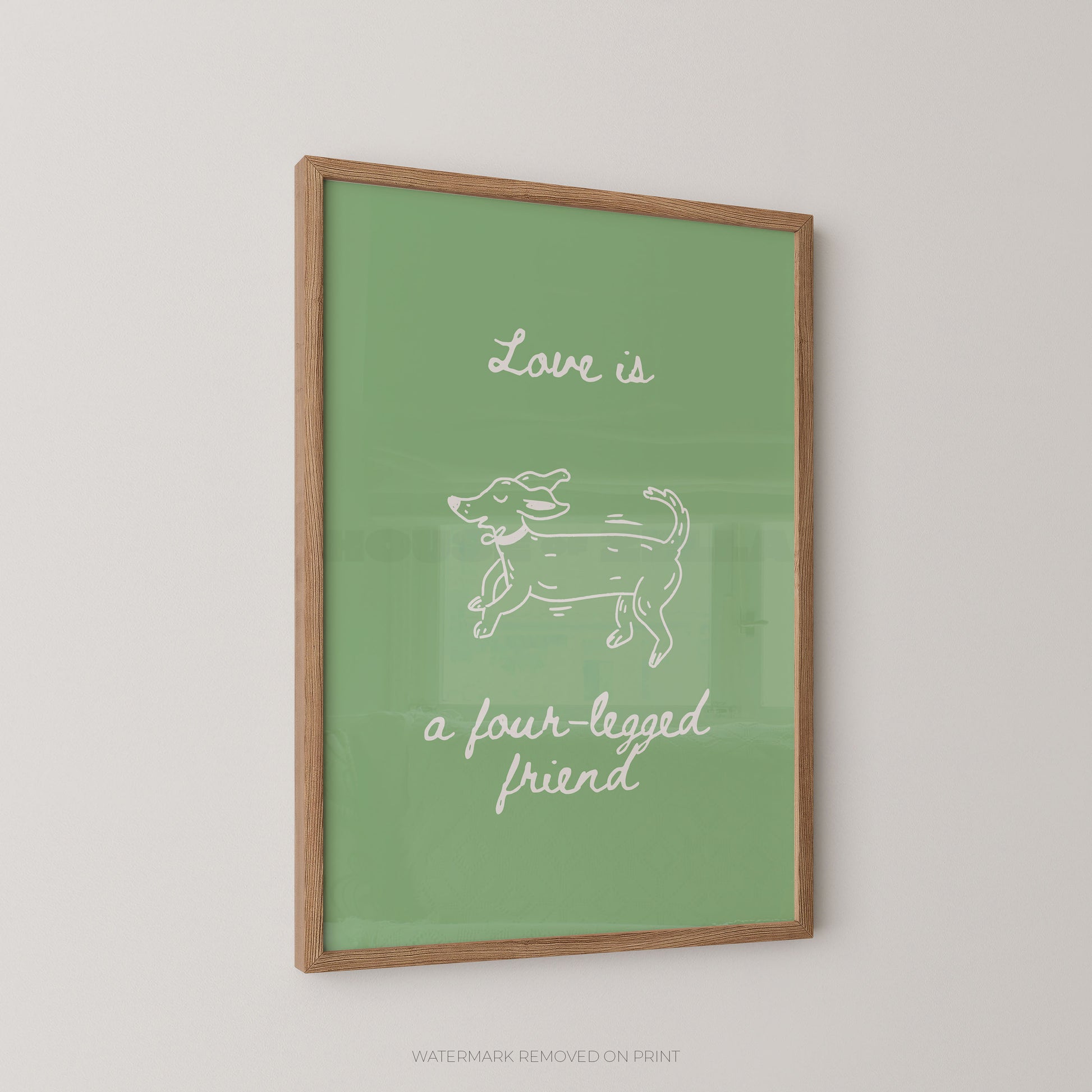 A framed art print featuring a green background with a white line drawing of a dog and the text 'Love is a four-legged friend' in white script, displayed on a light gray wall.