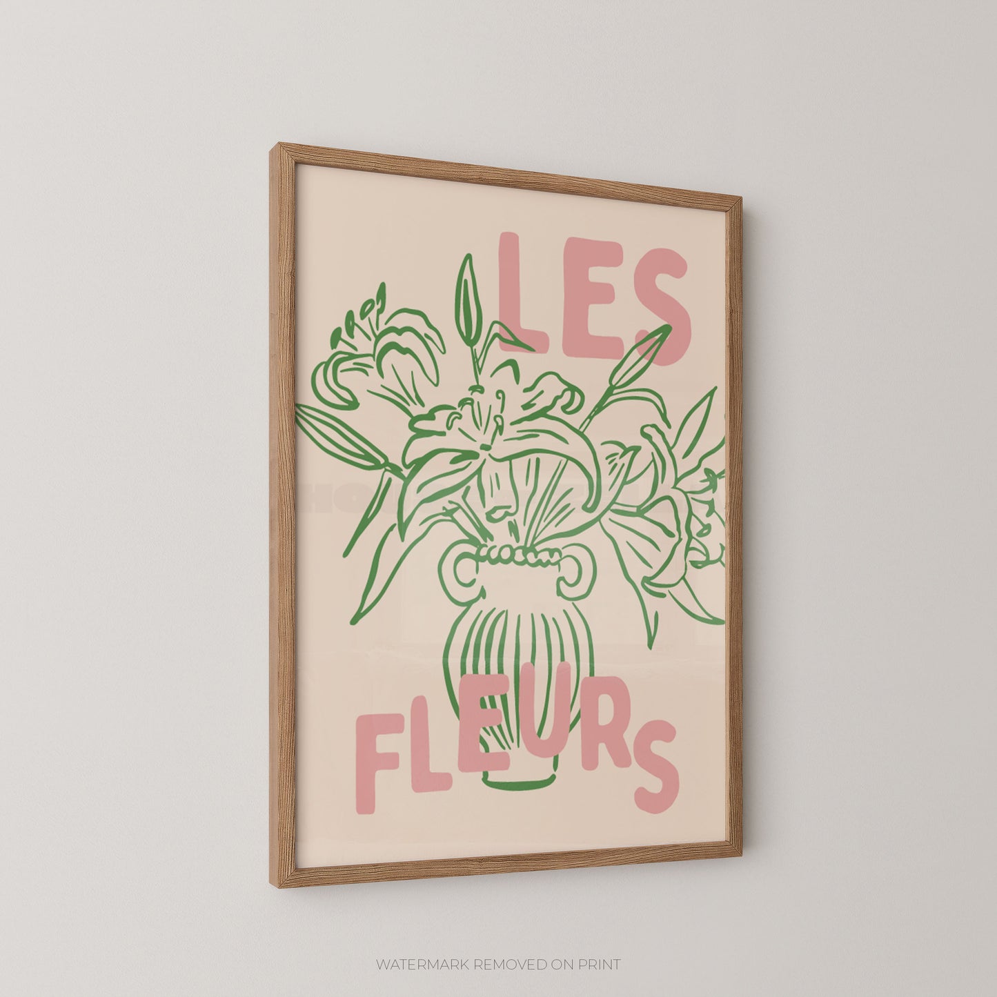 Framed wall art print with a beige background, green floral line drawing, and pink text reading “LES FLEURS,” shown hanging on a light gray wall.