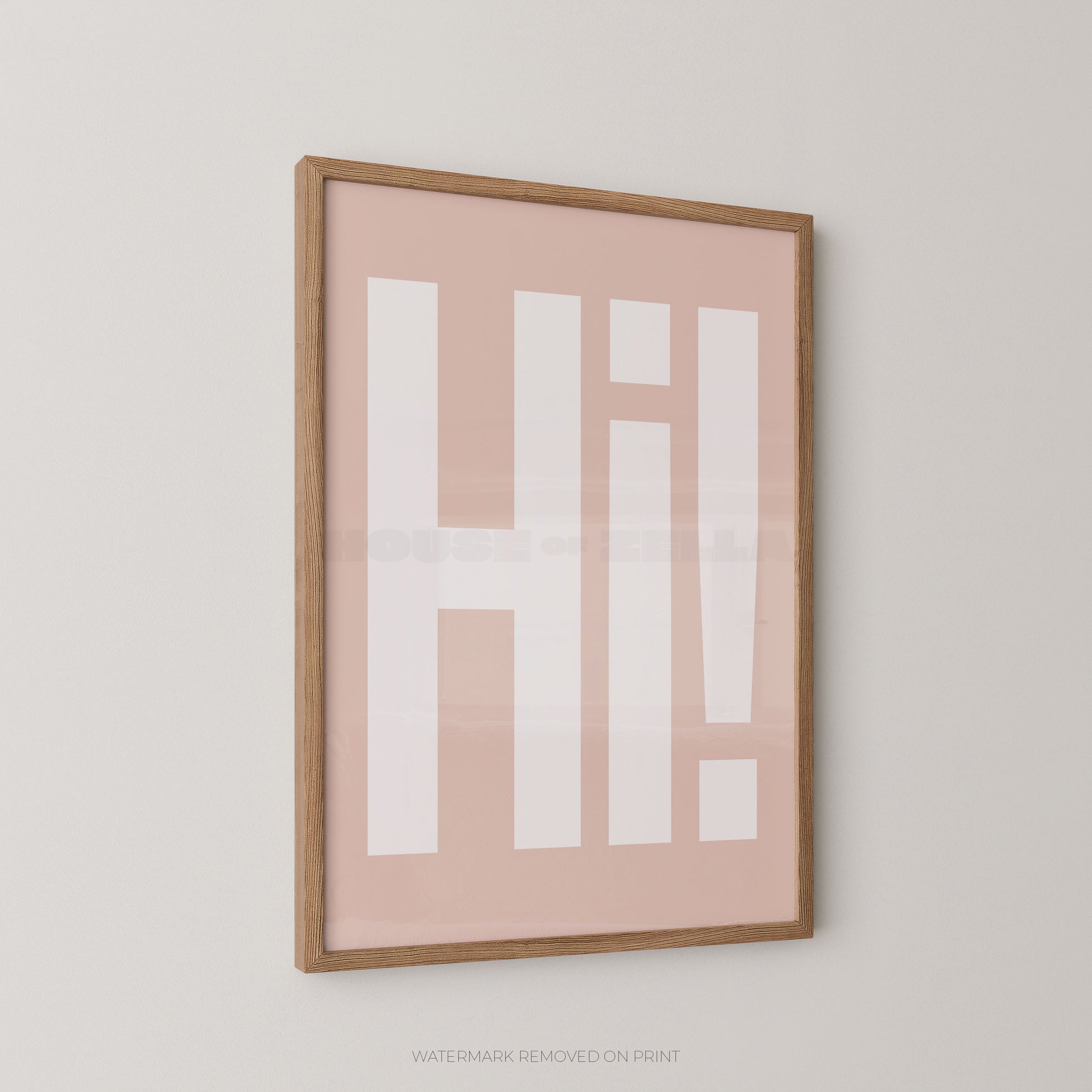 Framed minimalist wall art featuring the word 'HI!' in bold white block letters on a soft blush pink background, enclosed in a light natural wood frame and shown hanging on a light neutral wall.