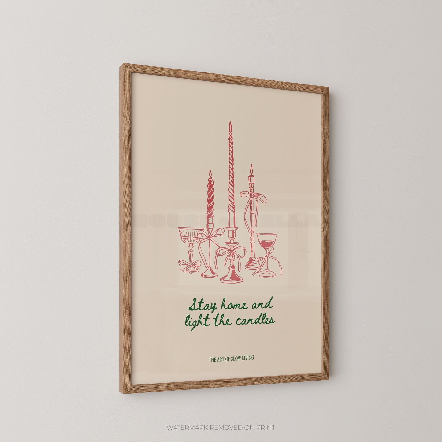 Framed art print featuring red line drawings of candles and glassware with the phrase 'Stay home and light the candles' in green script, hanging on a light gray wall.