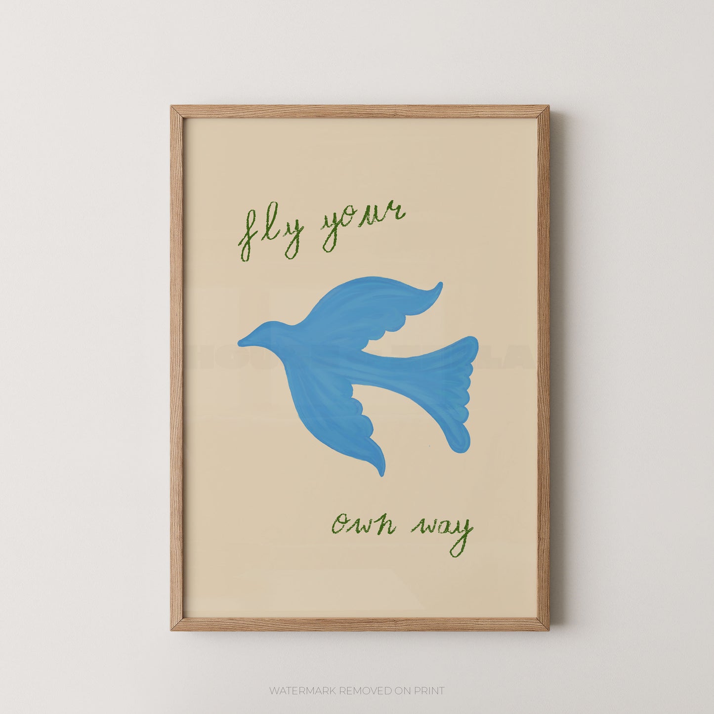 Framed wall art print with a light wood frame, featuring a blue bird illustration and the phrase 'fly your own way' in green script on a warm cream background.
