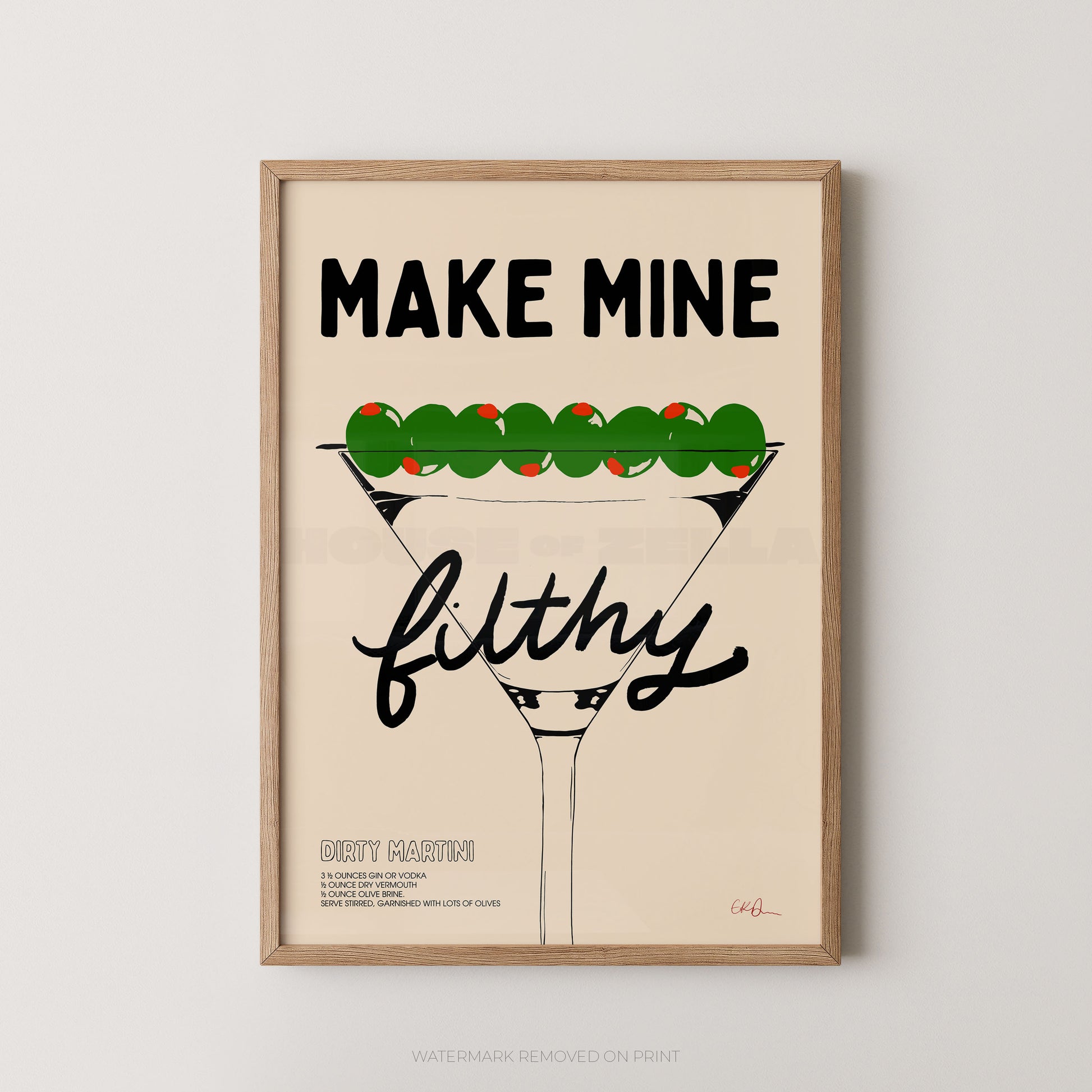 A framed typographic art print featuring a martini glass with green olives and the text 'MAKE MINE filthy' on a light beige background, shown against a light gray wall.