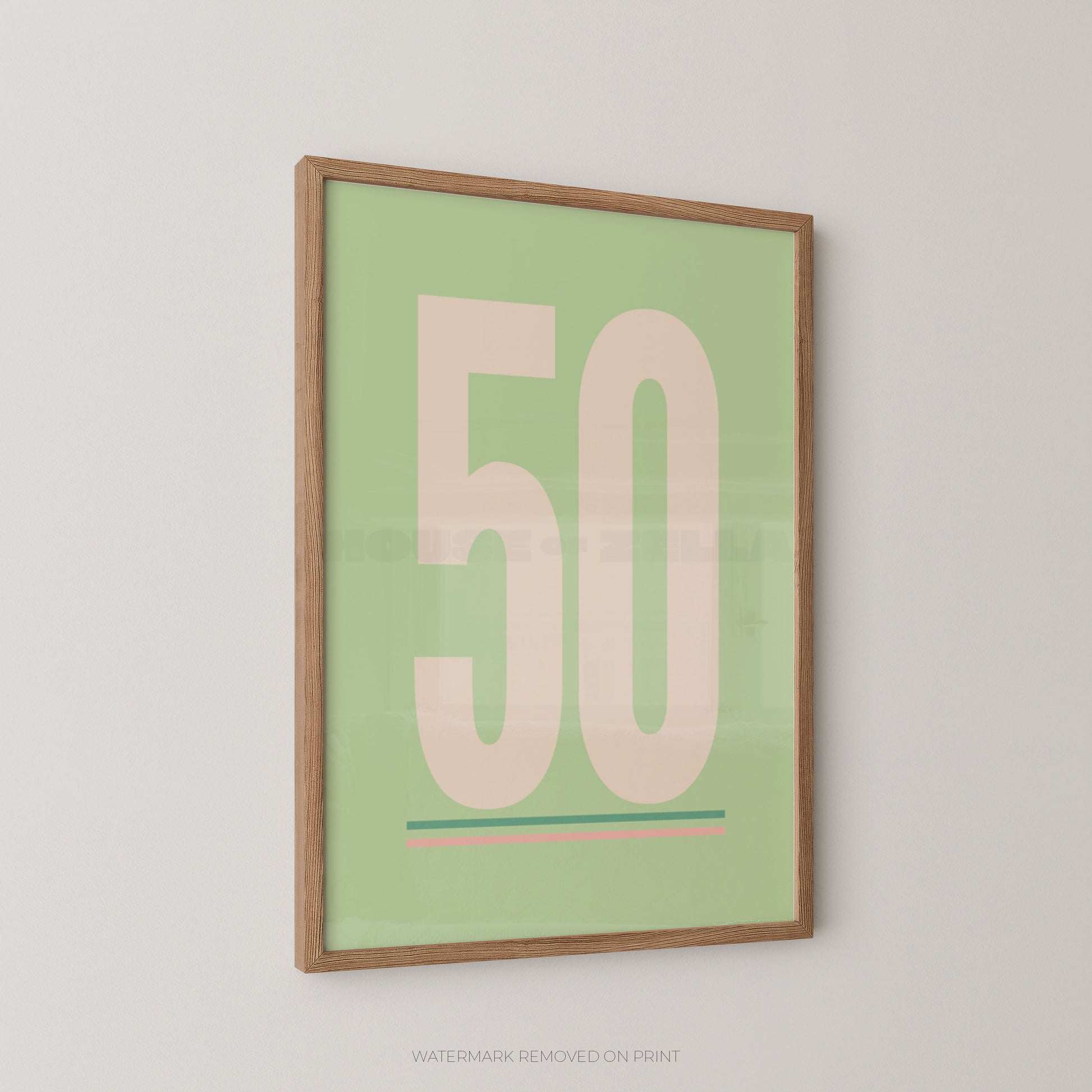 A framed minimalist art print featuring the number '50' in a pale pink color on a light sage green background, enclosed in a natural wood frame and displayed on a light gray wall.