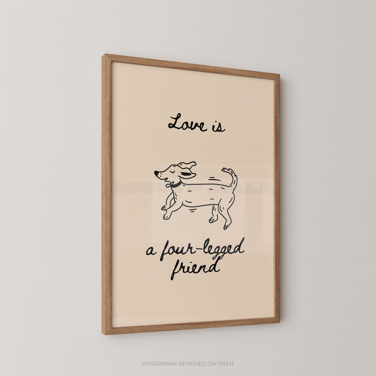 A framed wall art print with a light wood frame and cream background, featuring a simple black line drawing of a dog and the handwritten text 'Love is a four-legged friend' on a light gray wall.