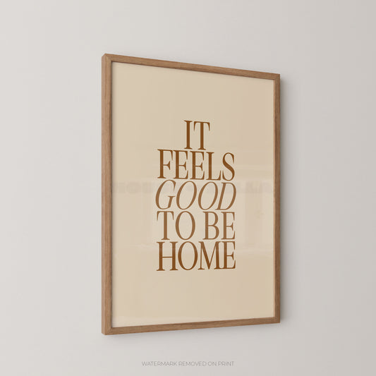 Framed print with 'It Feels Good to Be Home' text on a beige background