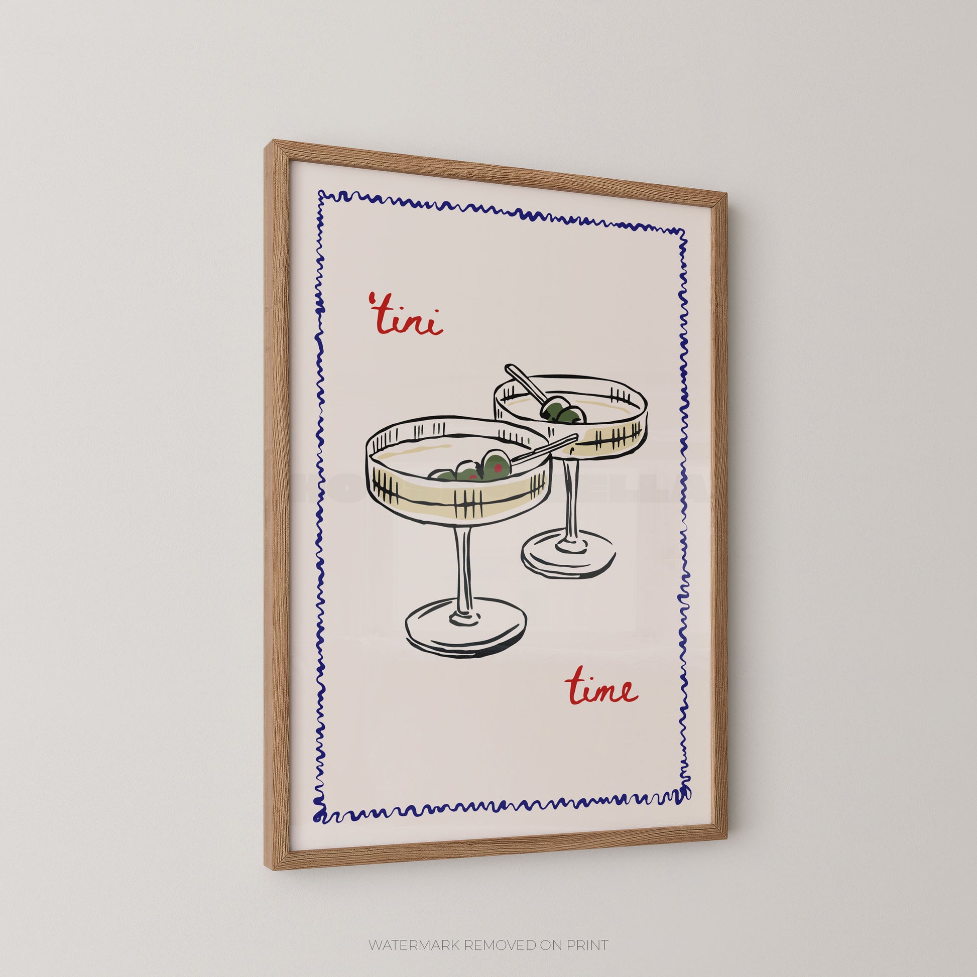 Framed wall art print featuring a hand-drawn illustration of two cocktail glasses with olives, bordered by a blue zigzag line, with the words "tini time" in red script, shown hanging on a light gray wall.