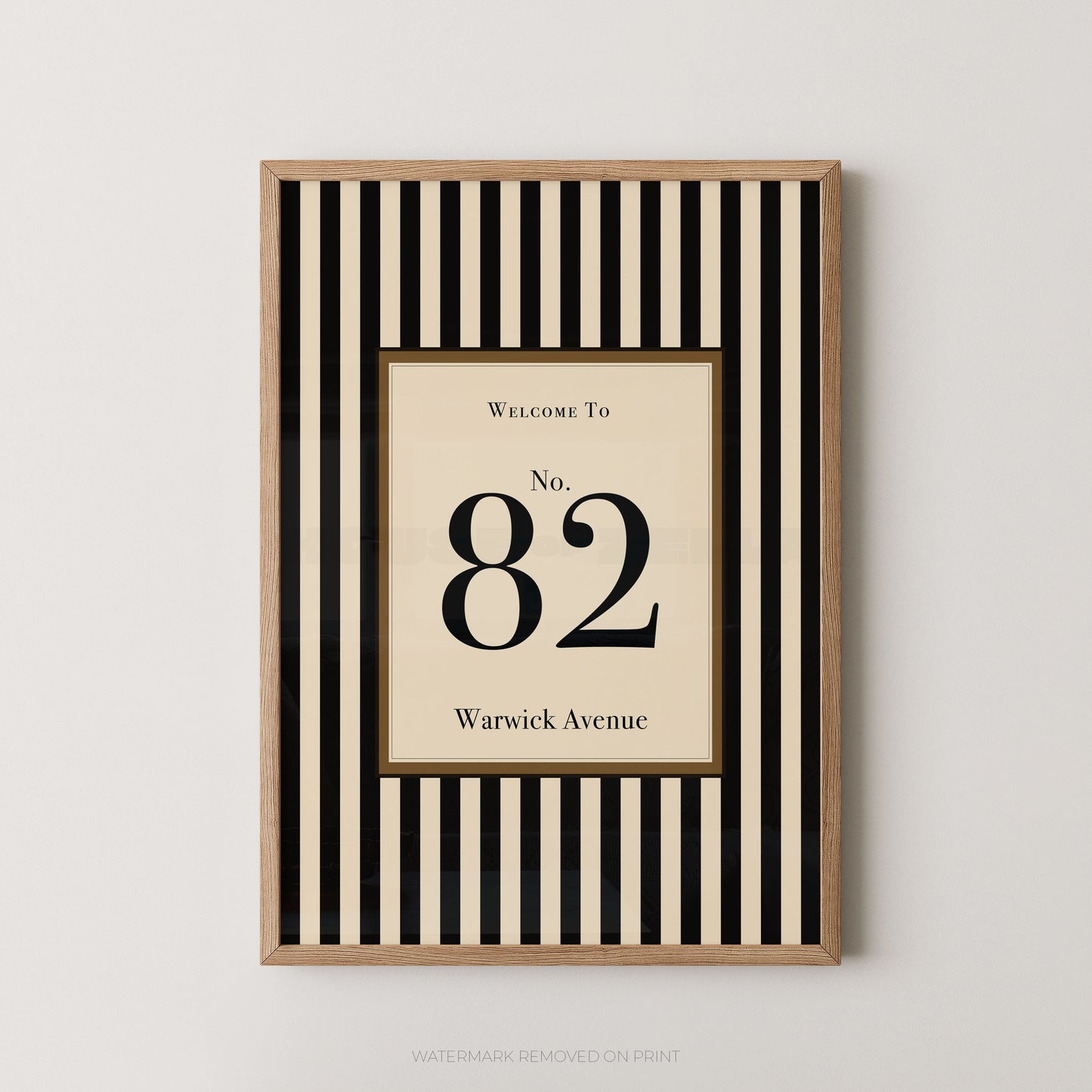 Framed vertical black and cream striped wall art with a central cream panel reading 'Welcome To No. 82 Warwick Avenue', shown hanging on a light neutral wall.
