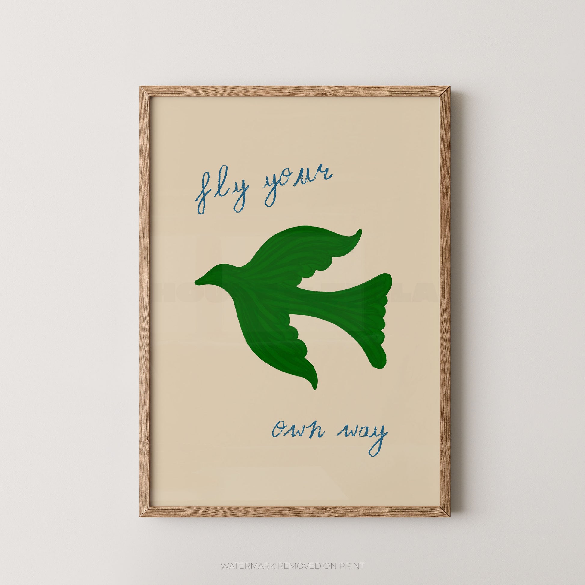 Fly your own way inspirational wall art print featuring a green bird silhouette in flight with blue handwritten script text on a cream background, displayed in an oak frame