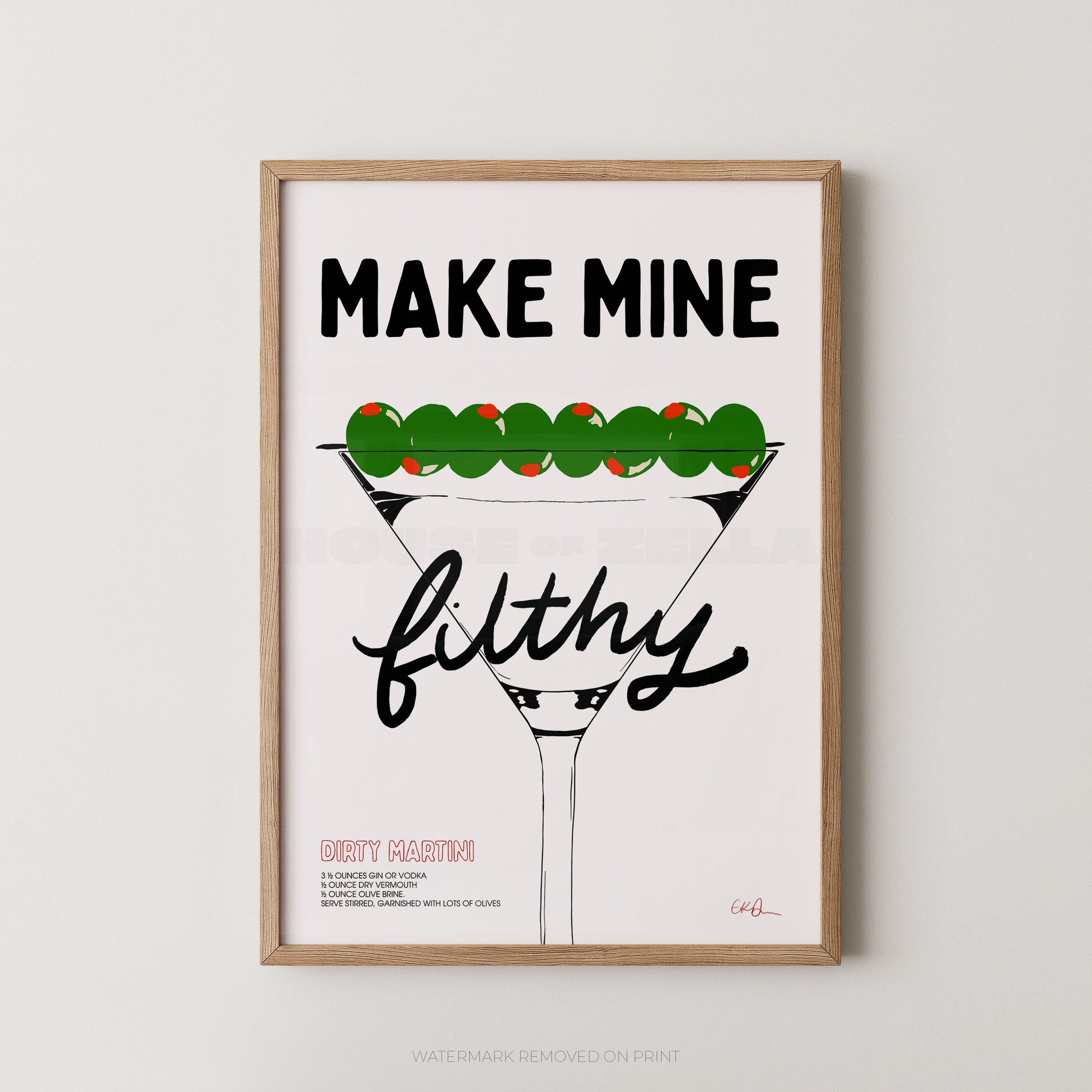 A framed typographic art print featuring a martini glass with green olives and the text 'MAKE MINE filthy' on a white background, shown hanging against a light gray wall.