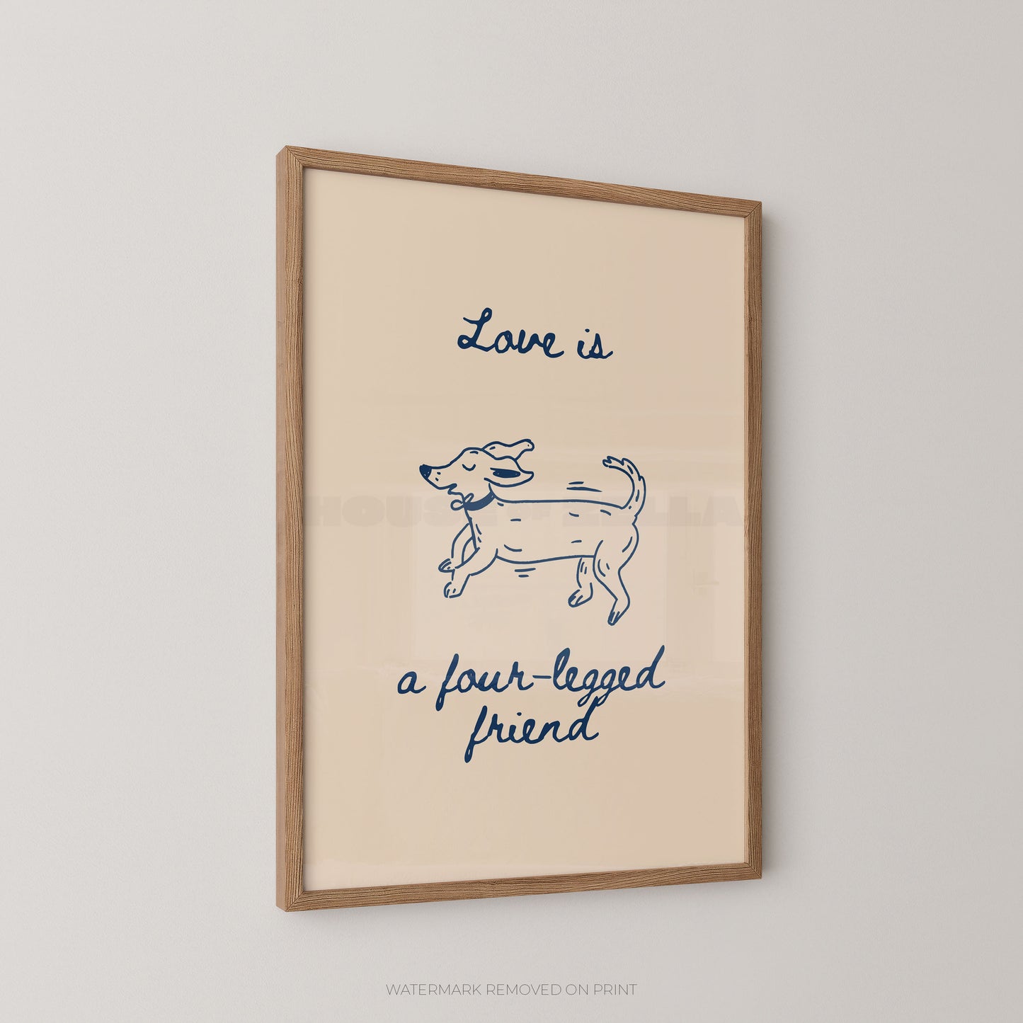 A framed art print featuring a pink background with a navy blue line drawing of a dog and the text 'Love is a four-legged friend' in blue script, displayed on a light gray wall.