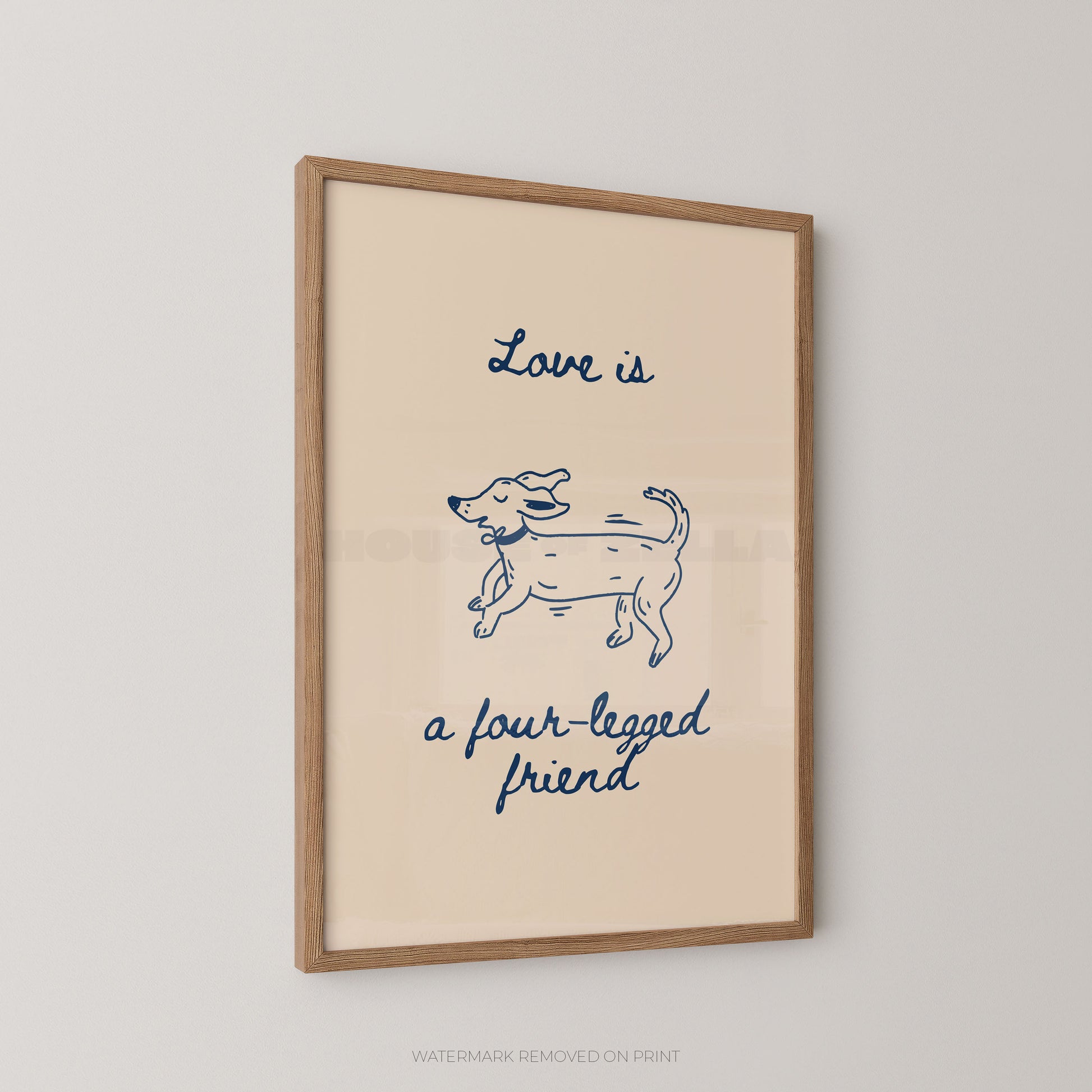 A framed art print featuring a pink background with a navy blue line drawing of a dog and the text 'Love is a four-legged friend' in blue script, displayed on a light gray wall.