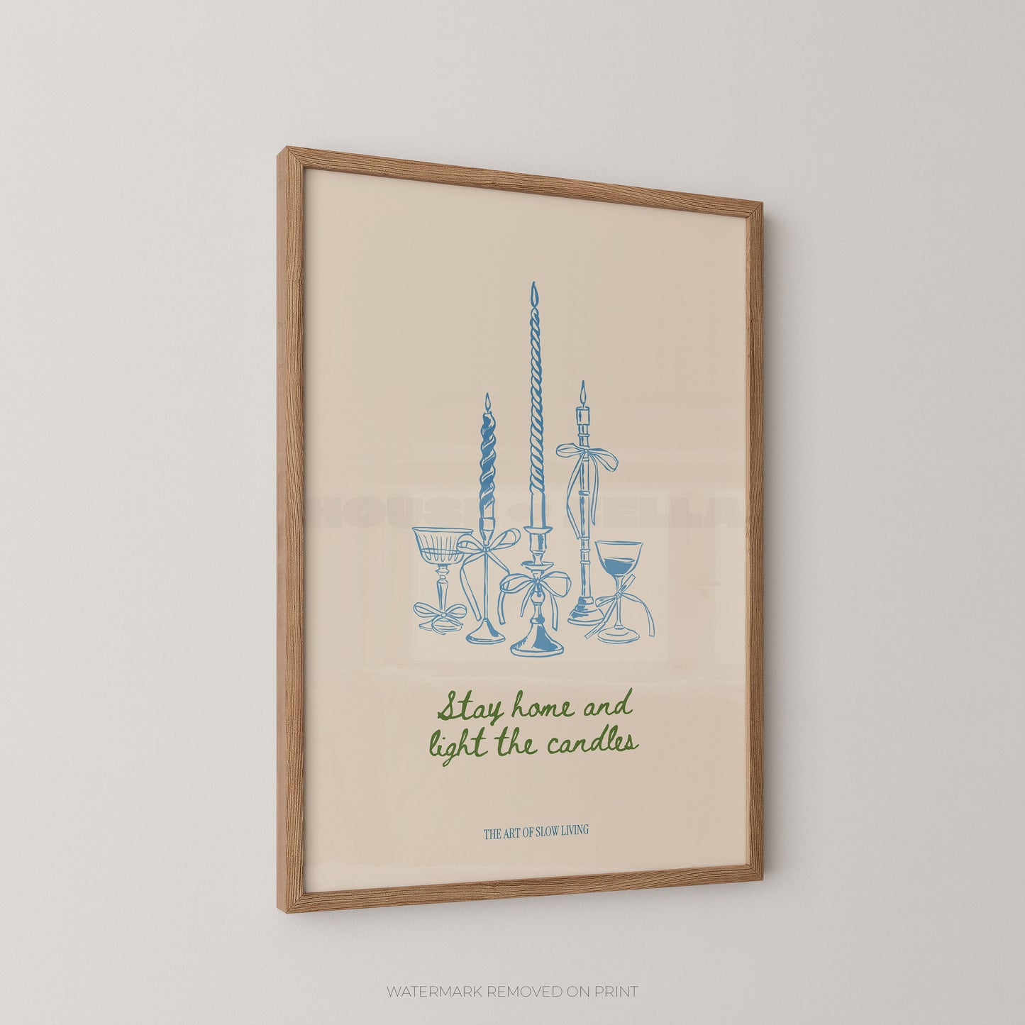 Framed art print featuring a blue line drawing of candles and glassware with the phrase 'Stay home and light the candles' in green script, displayed against a light neutral wall.