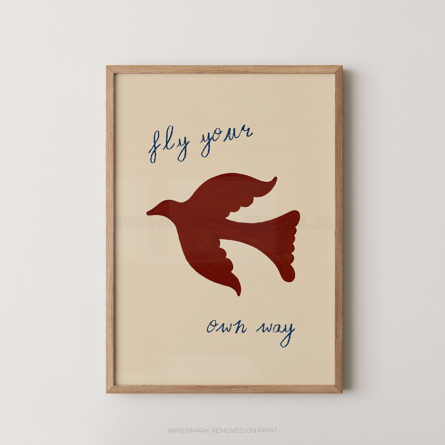 Framed wall art print with a beige background, a dark red dove silhouette in the center, and the phrase 'fly your own way' in blue script, shown in a light wood frame against a light gray wall.