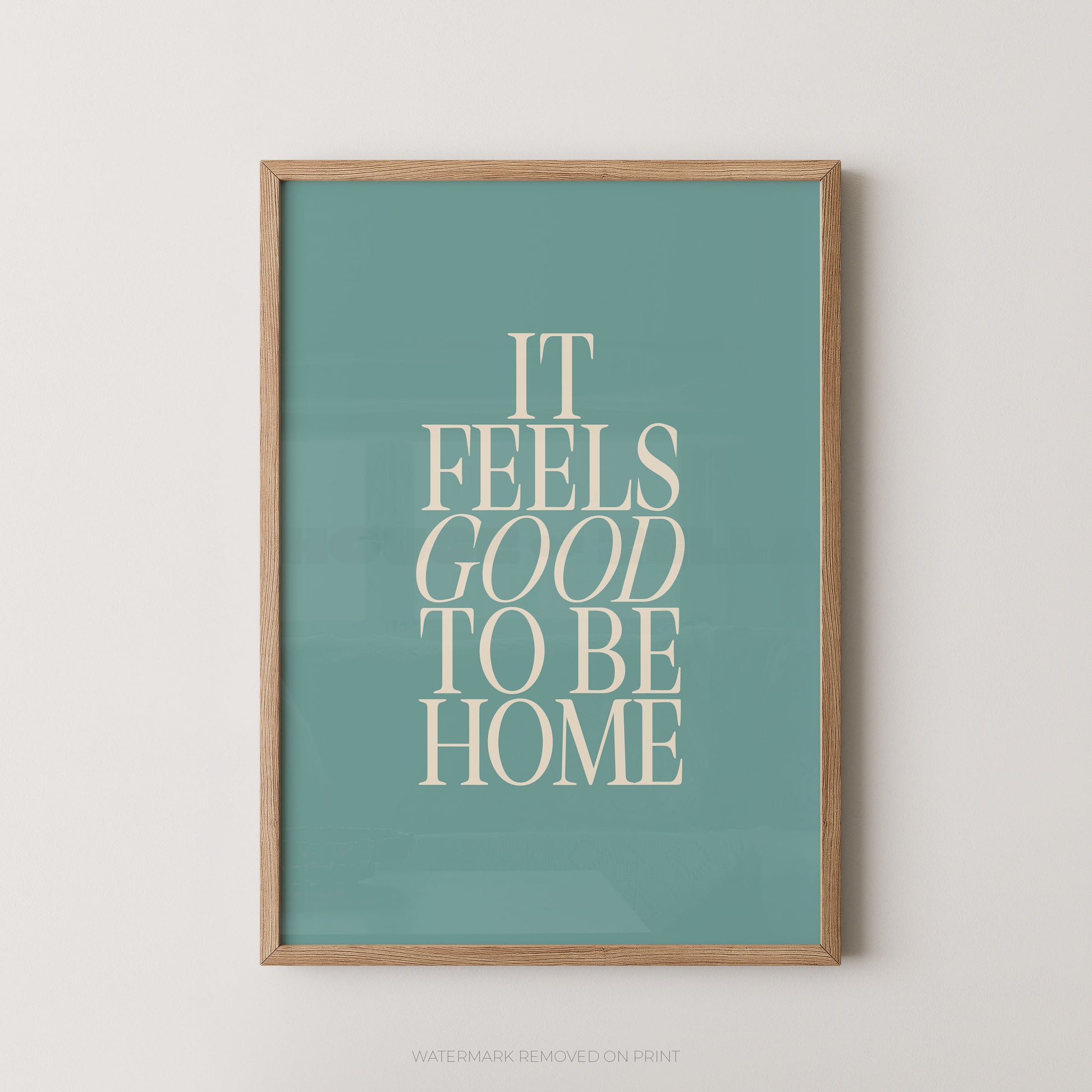 "It Feels Good To Be Home typography wall art print with elegant serif lettering in cream on a teal background, displayed straight-on in an oak frame"

