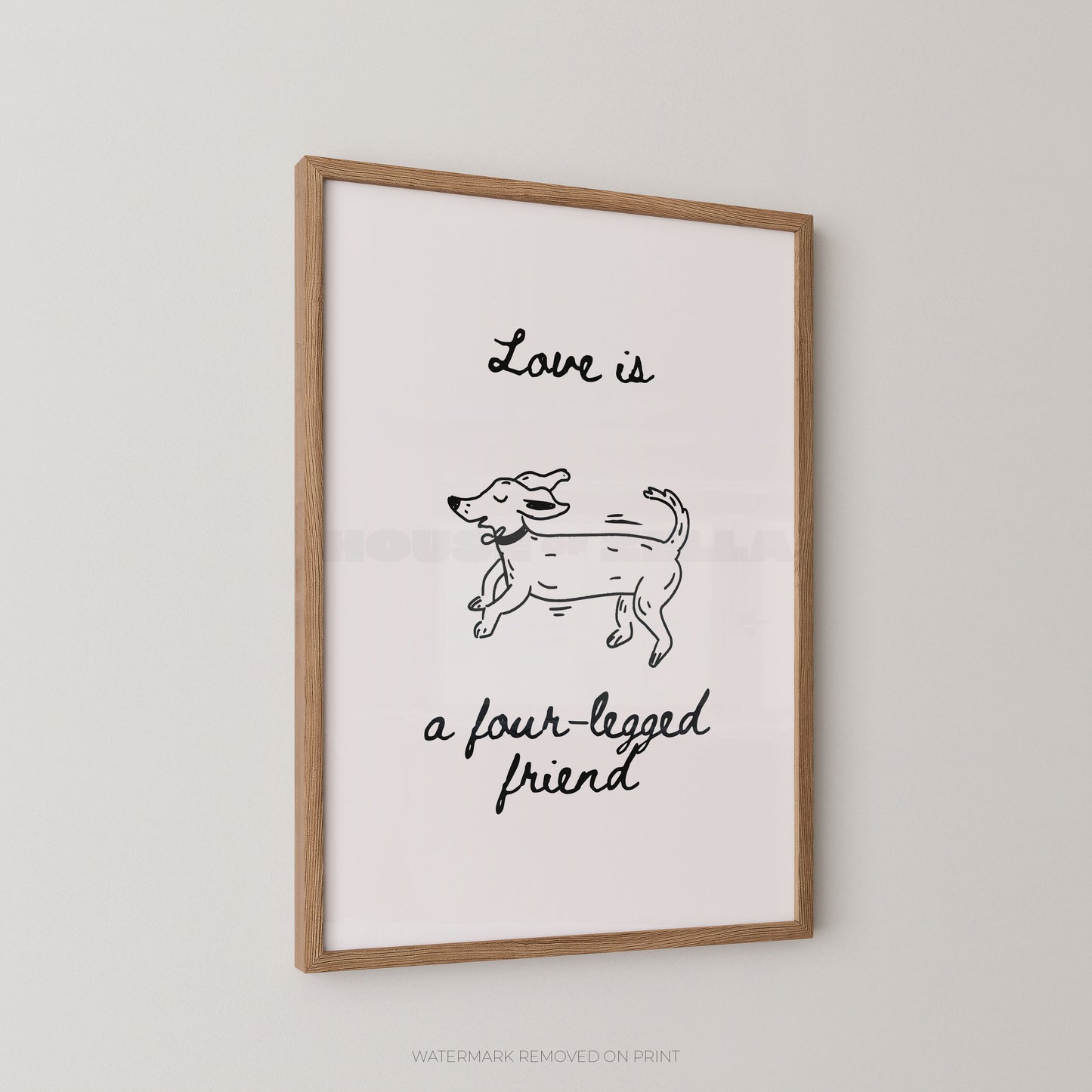 Framed wall art print with a light wood frame, featuring a simple black line drawing of a dog and the handwritten text 'Love is a four-legged friend' on a white background, shown hanging on a light gray wall.