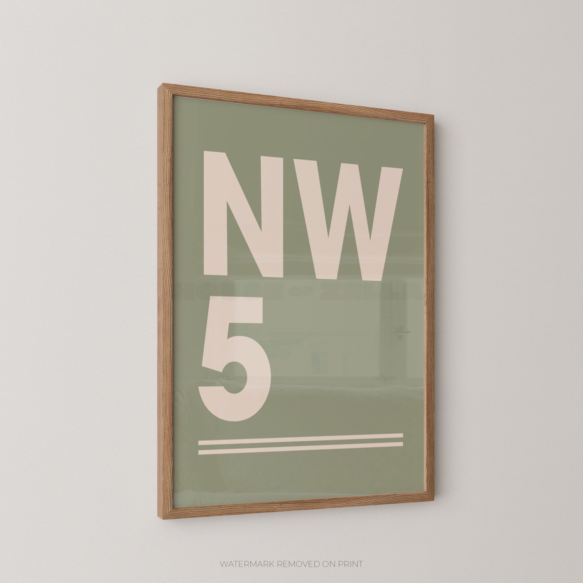 Framed minimalist wall art print with large cream lettering reading 'NW 5' on a muted sage green background, shown hanging on a light neutral wall.