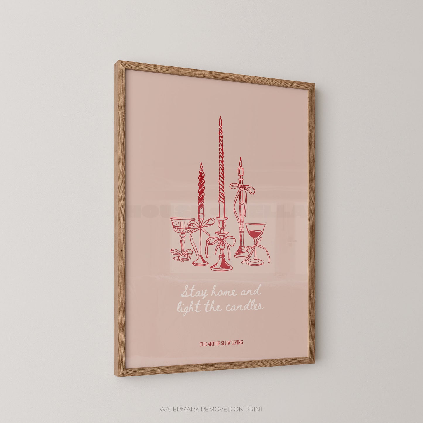 Framed art print featuring a minimalist red line drawing of candles, goblets, and a glass with the text 'stay home and light the candles' on a soft pink background, shown hanging on a light gray wall.