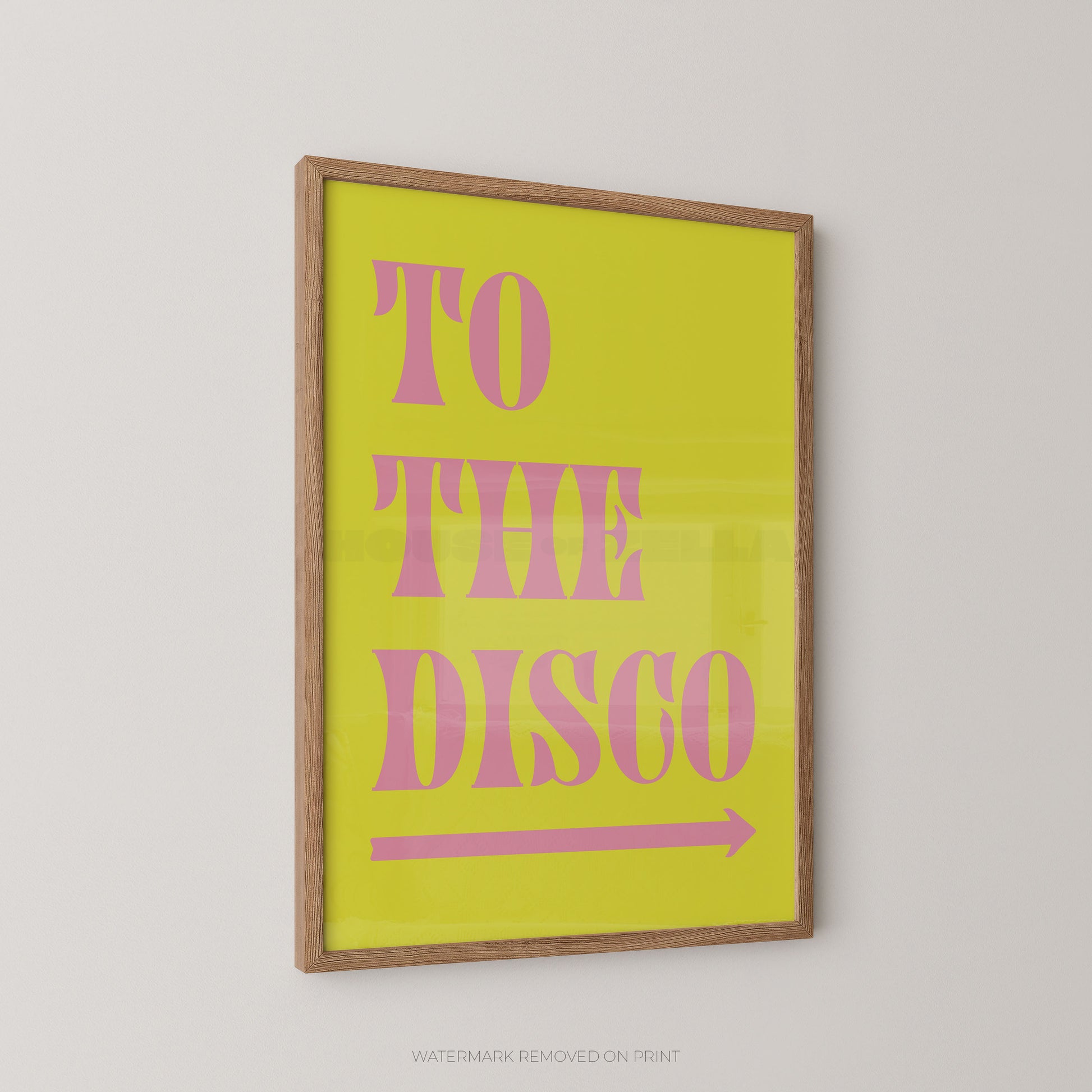 A framed typographic wall art print with the words “TO THE DISCO” in pink serif letters on a bright yellow background, shown hanging on a light gray wall.