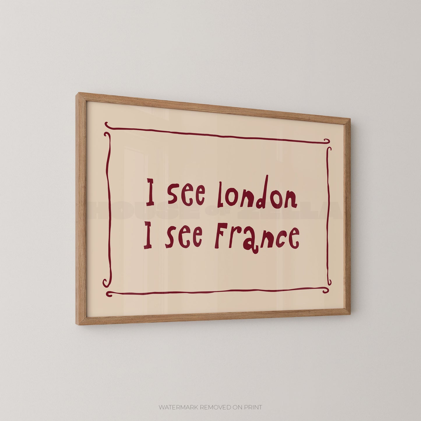 Framed wall art print with the handwritten text 'I see London I see France' in dark red inside a light wood frame, shown hanging on a light gray wall.